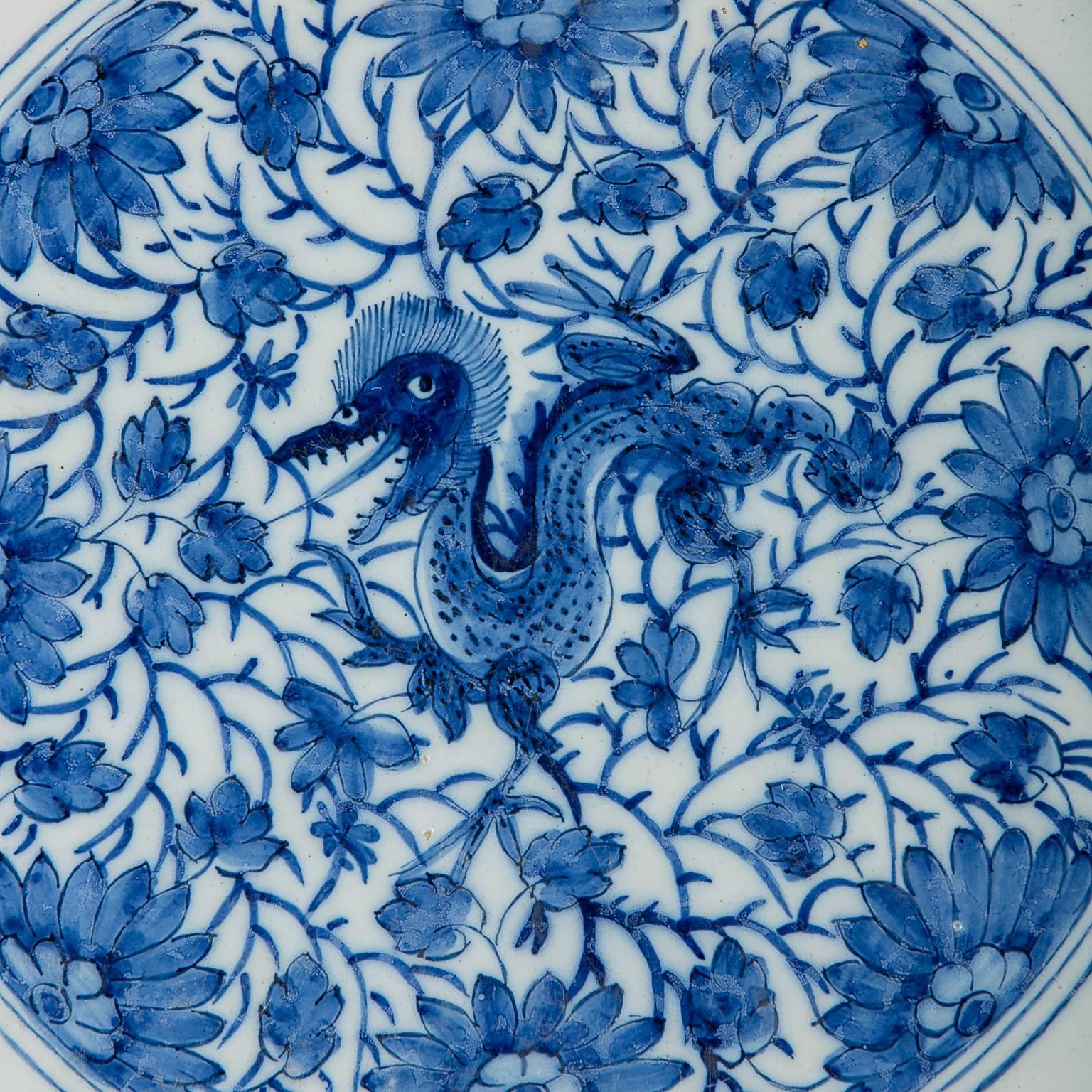A pair of 18th century blue and white Dutch Delft chargers decorated with dragons.
The mythical dragon in the center of these chargers is a rare motif on Delft plates. It has an open mouth, sharp teeth, hair standing on end, and sharp claws. The