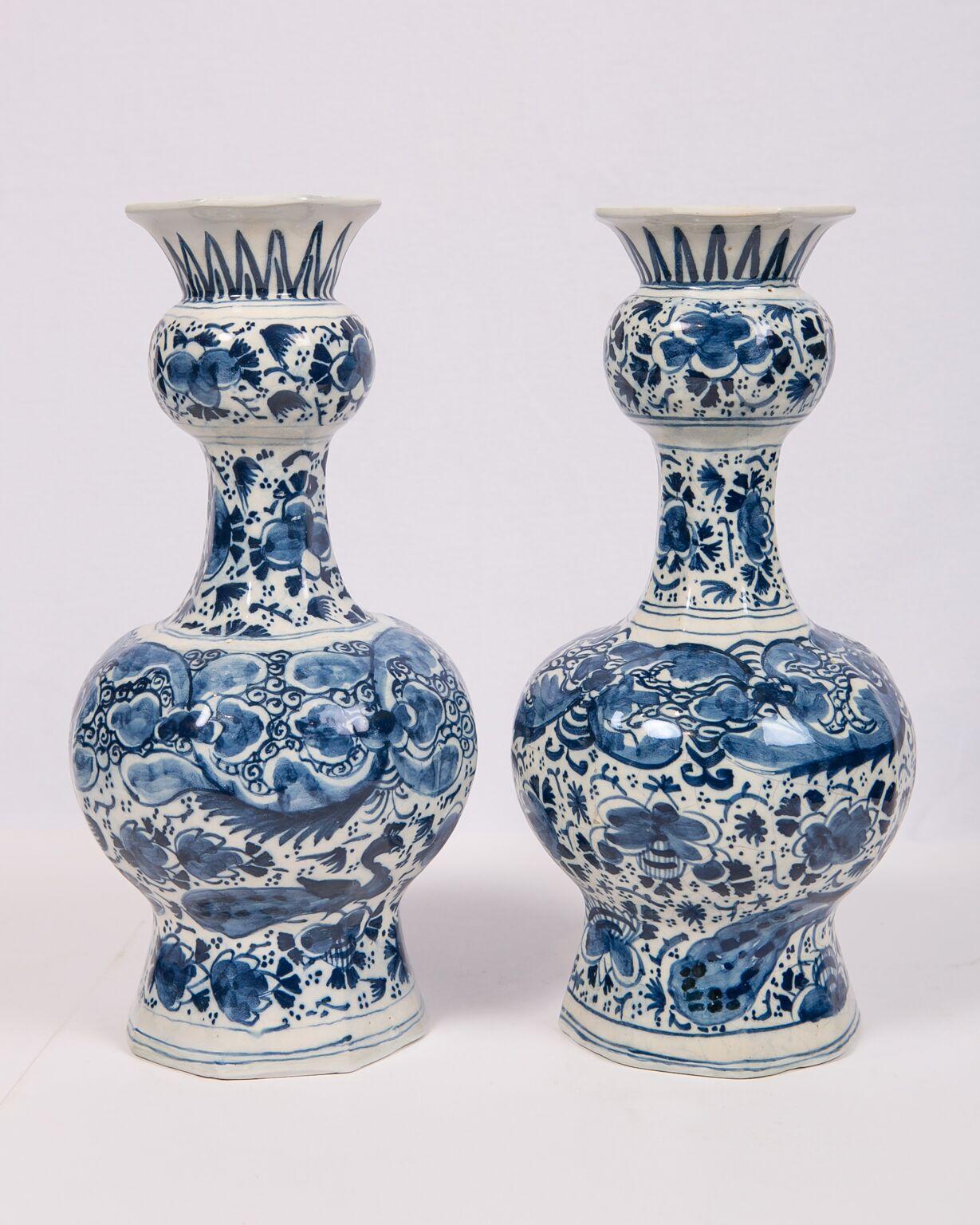 We are pleased to offer this pair of blue and white Dutch Delft vases painted in deep cobalt blue. Each vase is beautifully decorated with an all around design showing peacocks and a variety of flowers. The rounded octagonal shape of the vases is a