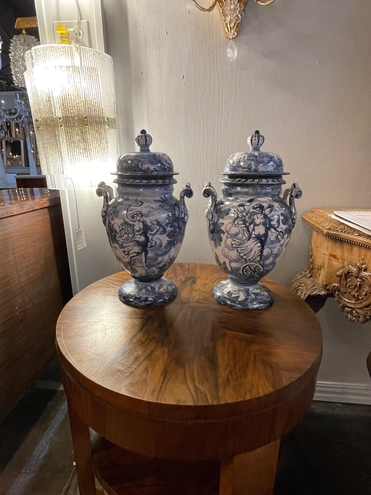 Beautiful pair of blue and white Faience glazed lidded urns. Lovely landscape and floral images along a lovely lady. Fabulous!