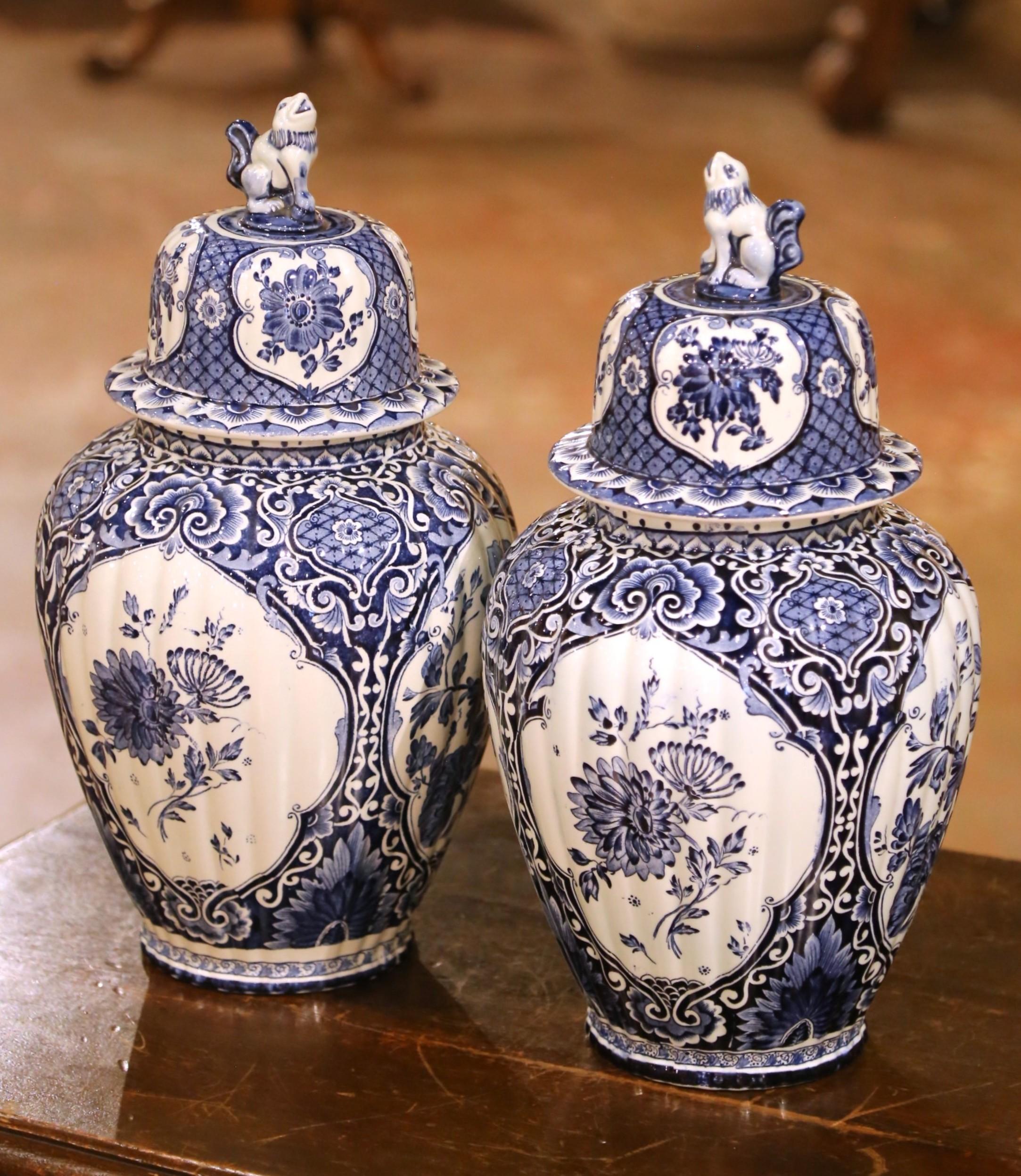 Aggiungi un fascino classico al tuo arredamento con questa squisita coppia di vasetti di zenzero con coperchio di Delft, Royal Sphinx, Maastricht. Dipinti a mano in Olanda verso la metà del XX secolo, questi sorprendenti vasi in maiolica bianca e
