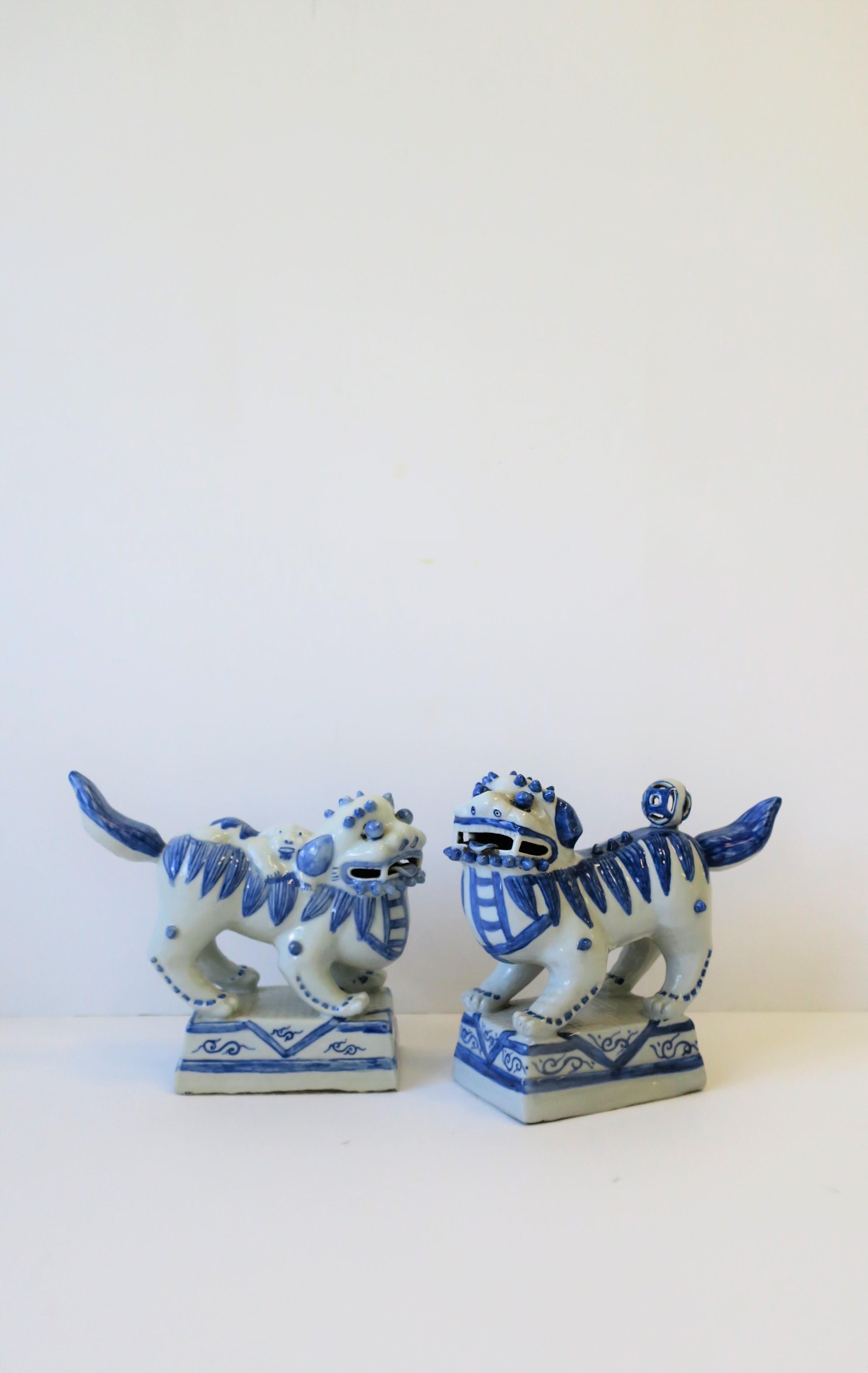 A vintage pair of blue and white foo dog or lion sculptures, decorative objects, or bookends. Both dogs/lions have a kinetic tail (tail 'wags' or moves up and down slightly.)

Measurements: 8.75 in. H x 10 in. D x 4.25 in. W.
 