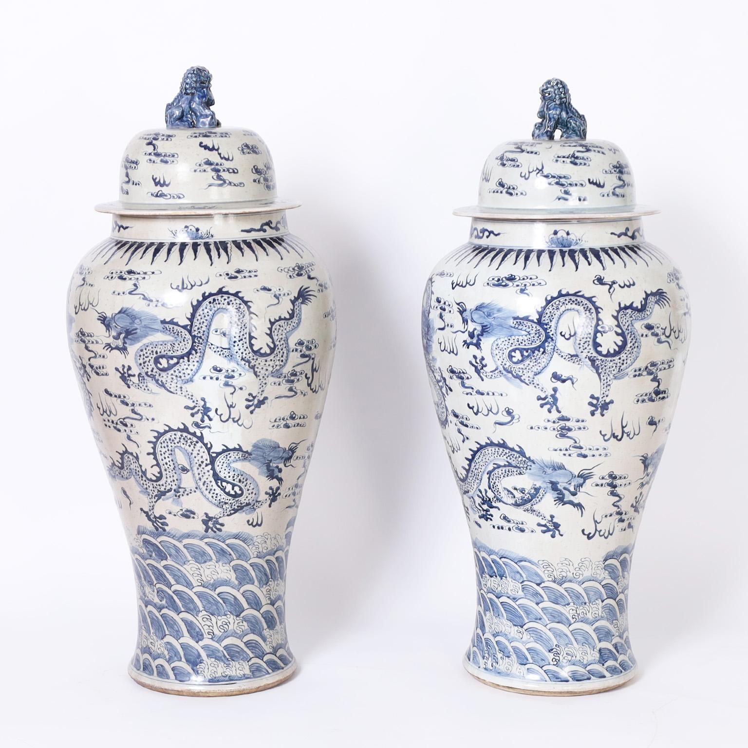 Pair of palace urns with a bold scale and featuring foo dog handles on top as guardians and hand decorated with a dragon motif.