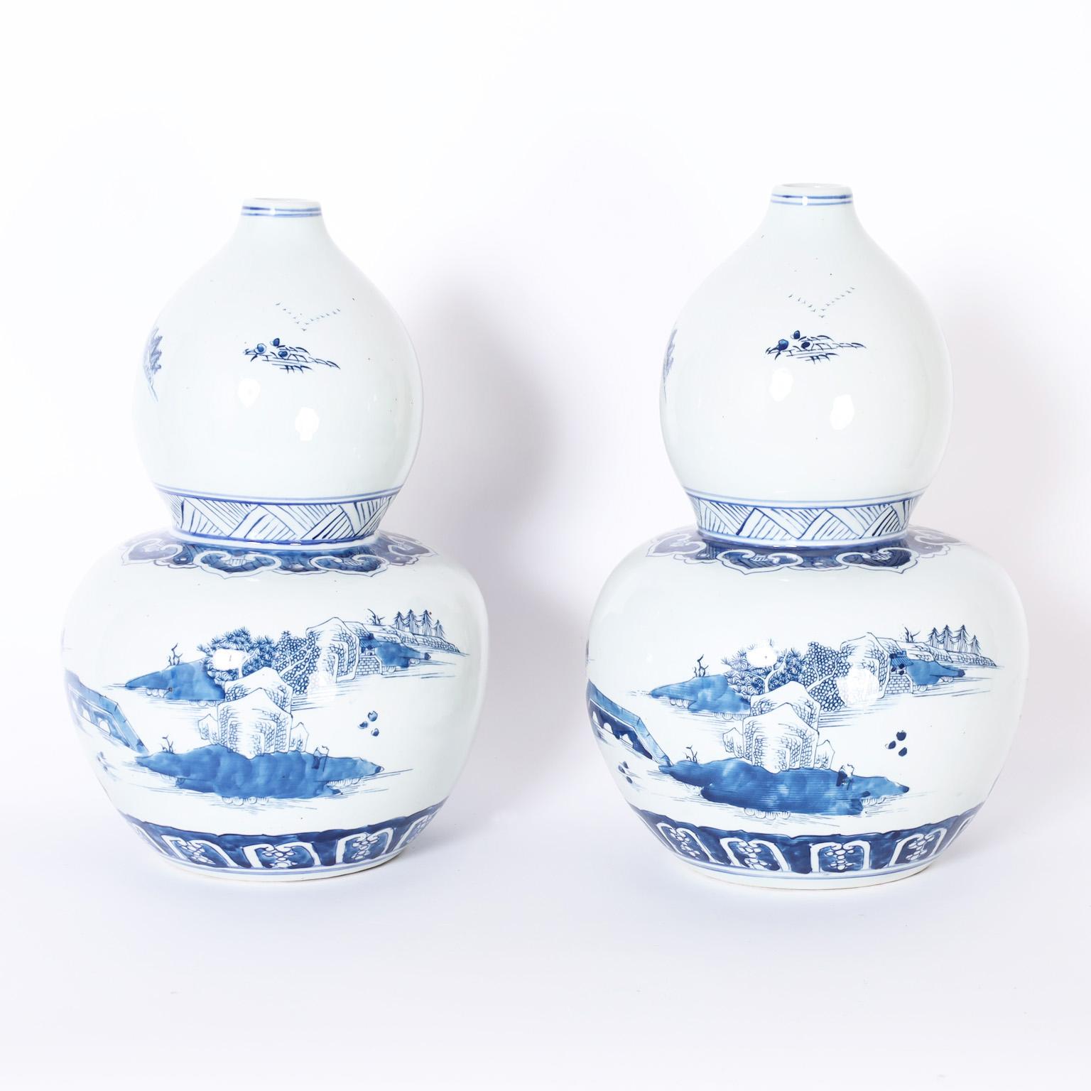 Pair of Chinese blue and white porcelain vases with a classic double gourd form hand decorated with pagodas in landscapes, in the Chinese Export manner.