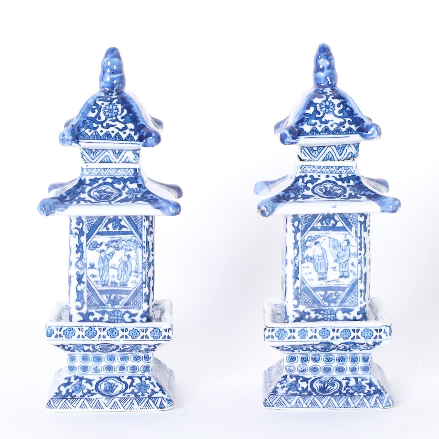 Pair of petite Chinese blue and white porcelain canisters or caddies with an elegant pagoda form hand decorated with floral and geometric designs around center panels with figures.