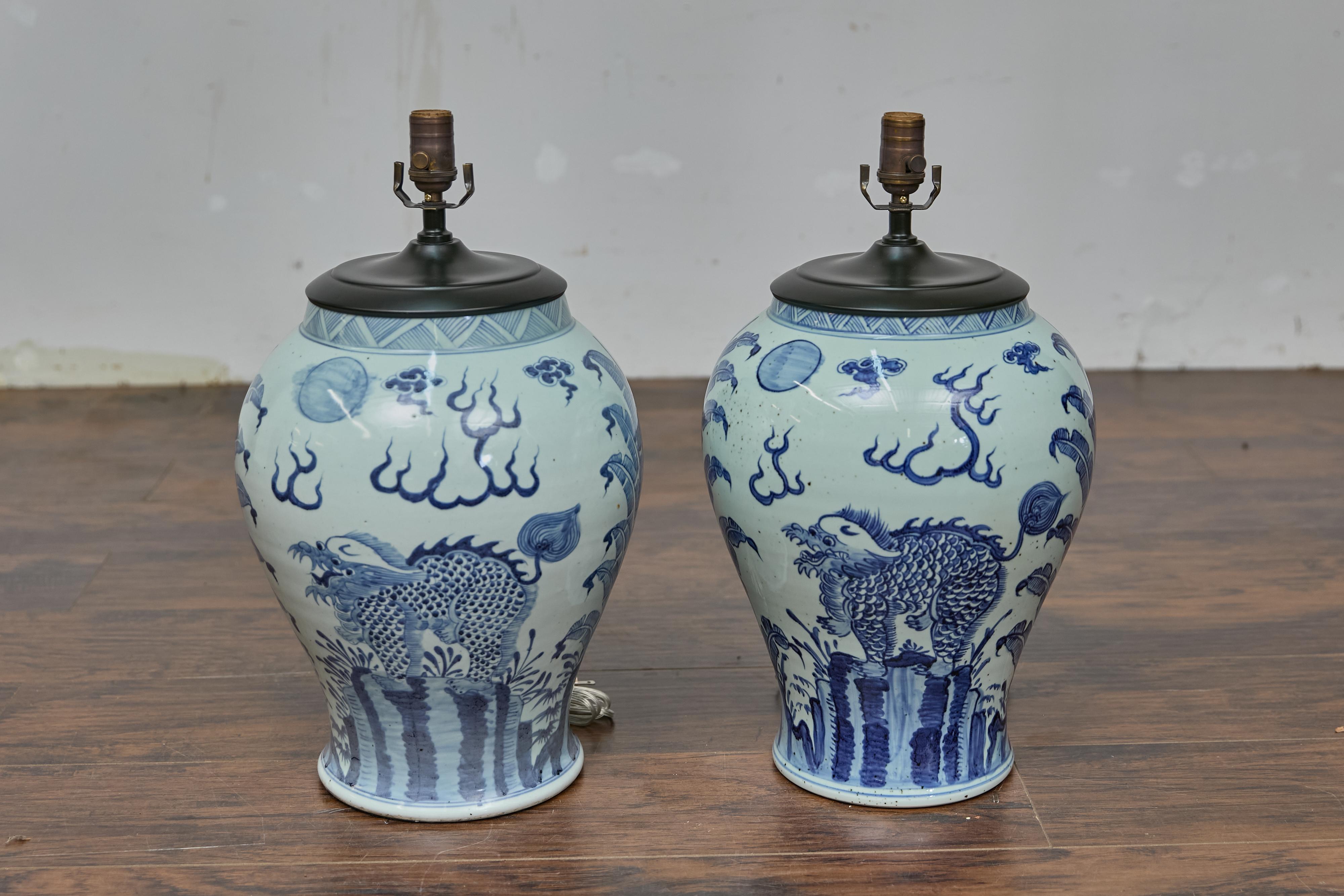 Coppia di lampade da tavolo da altare in porcellana bianca e blu, ognuna riccamente decorata con intricate pennellate che raffigurano il mitico Qilin - un simbolo di buon auspicio di prosperità e protezione - con motivi di nuvole vorticose. Il