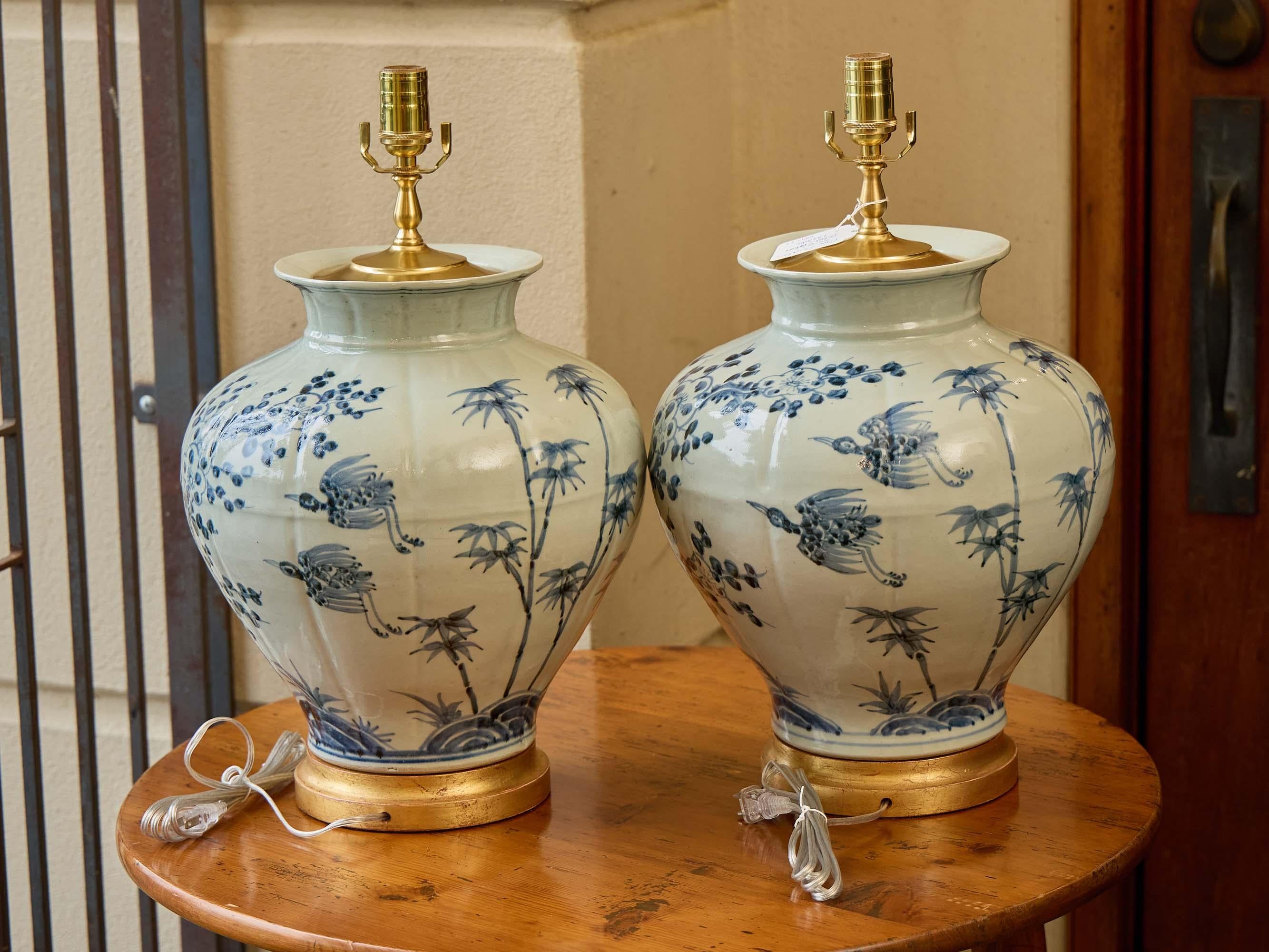 Asiatico Coppia di lampade a vaso in porcellana bianca e blu con pennellate floreali e base dorata in vendita
