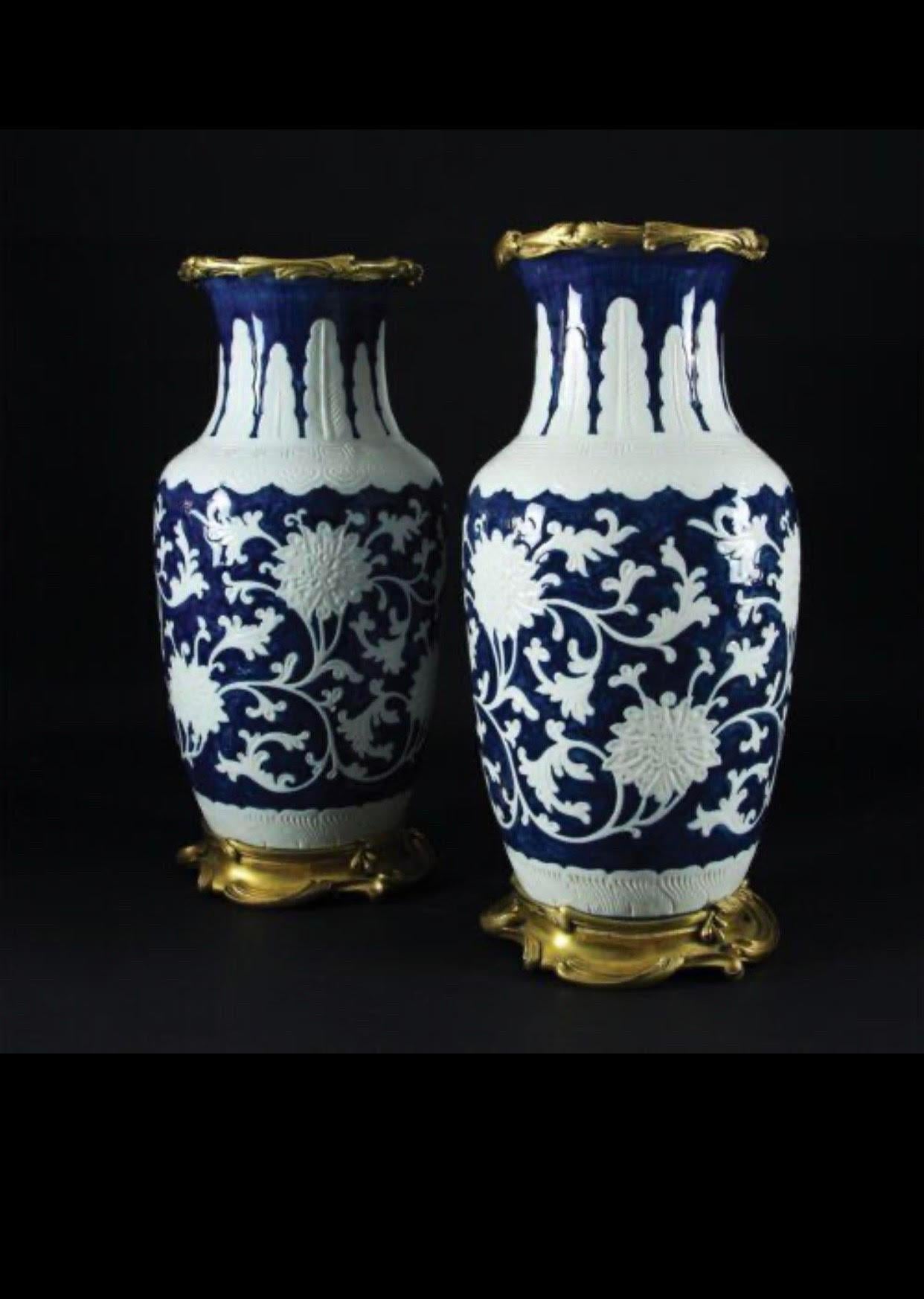 Élégante paire de vases en porcelaine bleue et blanche finement décorés de motifs floraux ; monture en bronze doré et ciselée de volutes. Chine, 19ème siècle. Dimensions 48x19x19cm.