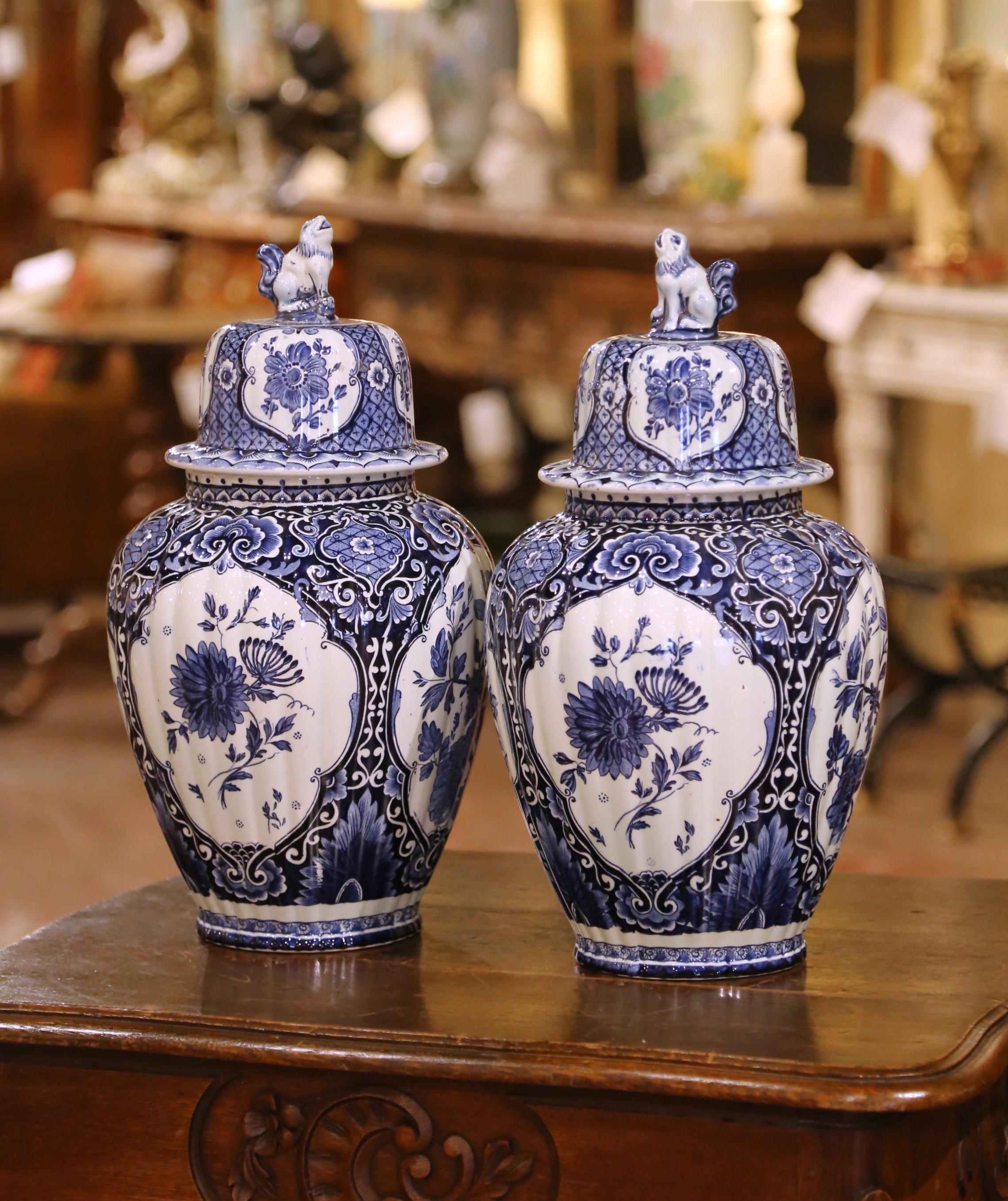 Añade encanto clásico a tu decoración con este exquisito par de tarros de jengibre de Delft con tapa, de Royal Sphinx, Maastricht. Pintados a mano en Holanda hacia 1950, estos llamativos jarrones de loza azul y blanca presentan un rico motivo floral