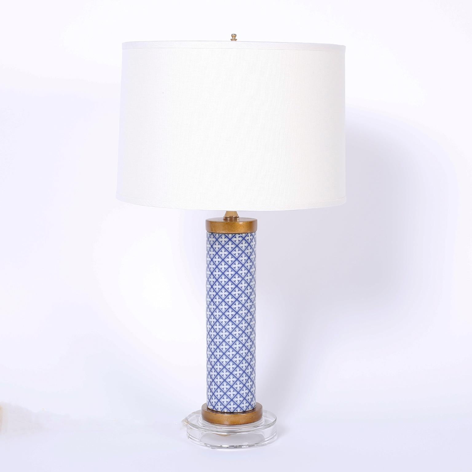Chic pair of modern glass table lamps with reverse printed repeating blue and white floral emblems under a classic canister form while presented on Lucite bases.