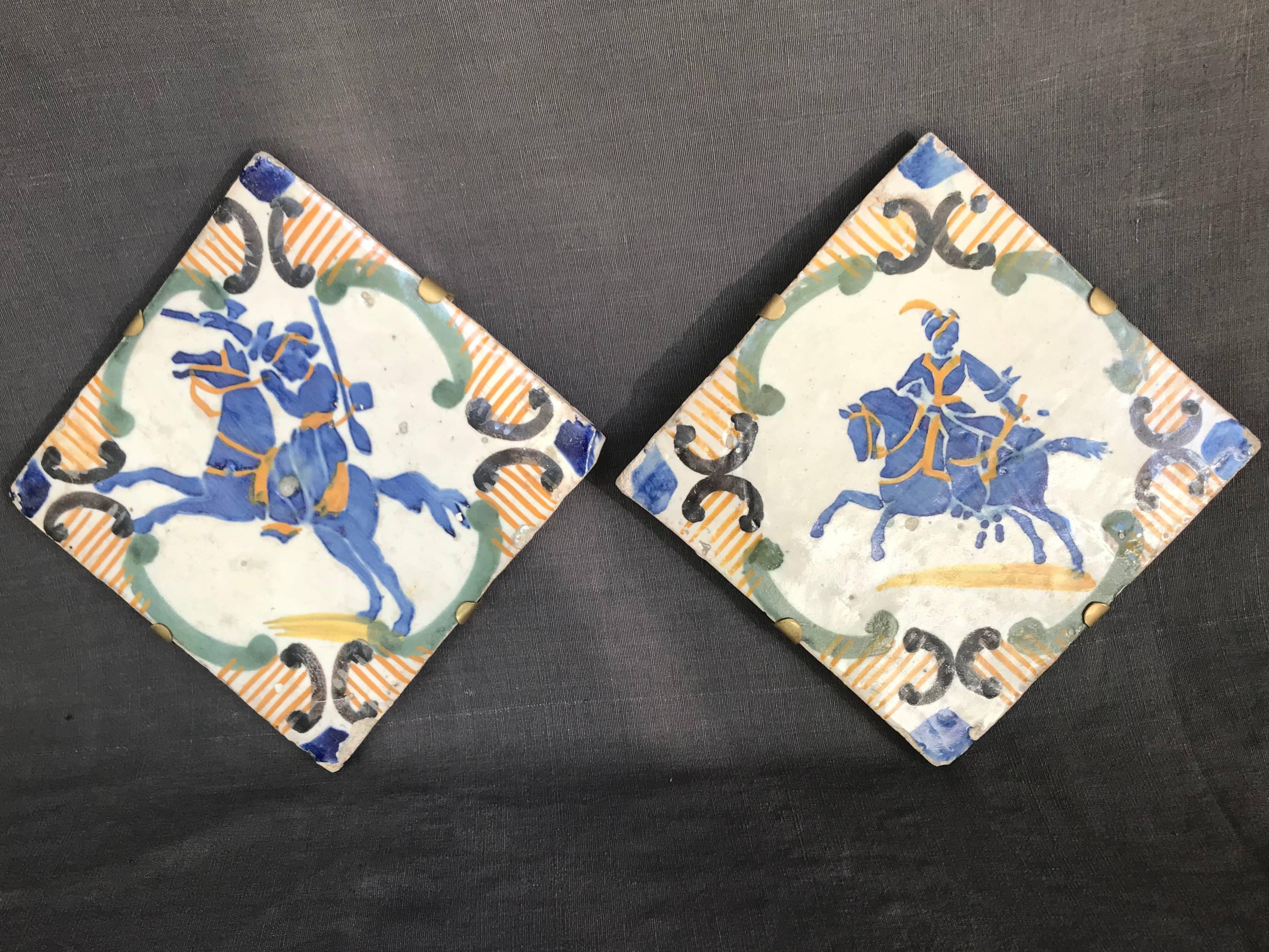 Pair of blue and yellow Neapolitan tiles. Pair of large equestrian-themed floor tiles of bold blue and yellow design featuring mounted huntsmen, of Italian and Arabic riders with hunting accoutrement; with custom brass hanging armature. Naples