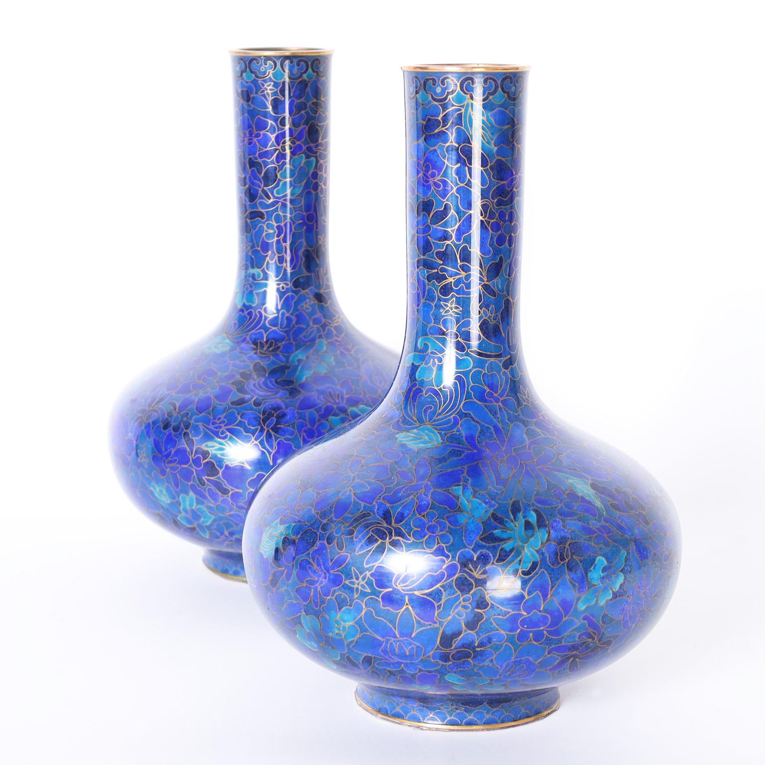 Striking in their beauty a pair of vintage Chinese cloisonne vases with classic form and featuring alluring blue floral designs. JINGFA label on the bottom.