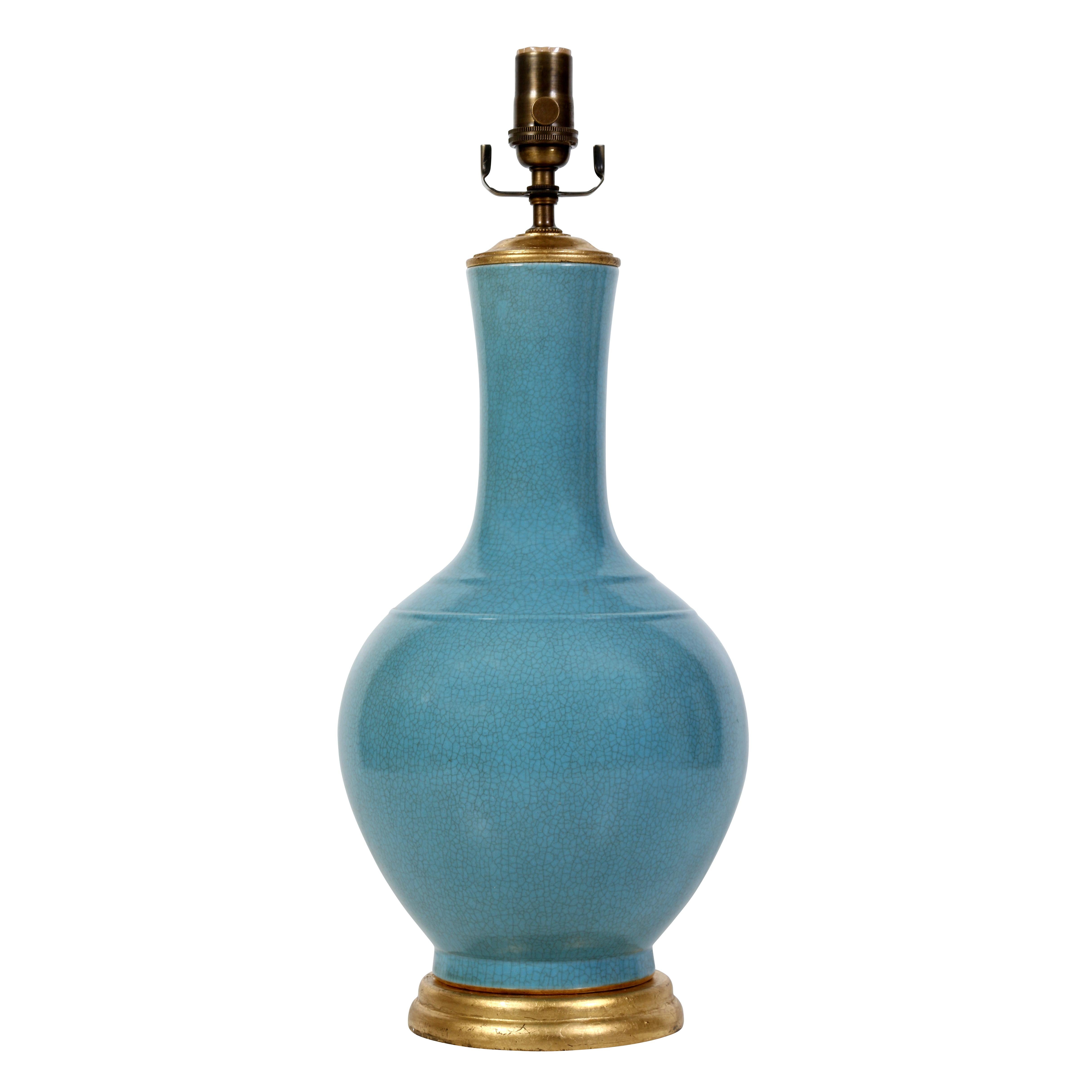 A pair of Chinese export lamps in a stunning robins's egg blue on a gilt base. The finish has a subtle crackle detail, adding a bit of depth. The urn-shaped lamps are in a medium scale, making them quite versatile--they would work on bedside tables,