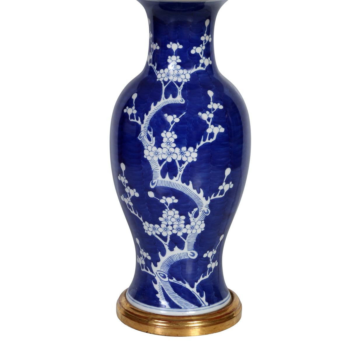 A pair of blue and white Chinese Export lamps sitting on 18 karat gold bases.  The blue lamps are beautifully decorated with white branches, leaves and flowers. A stunning pair of chinoiserie table lamps.  Shades sold separately.