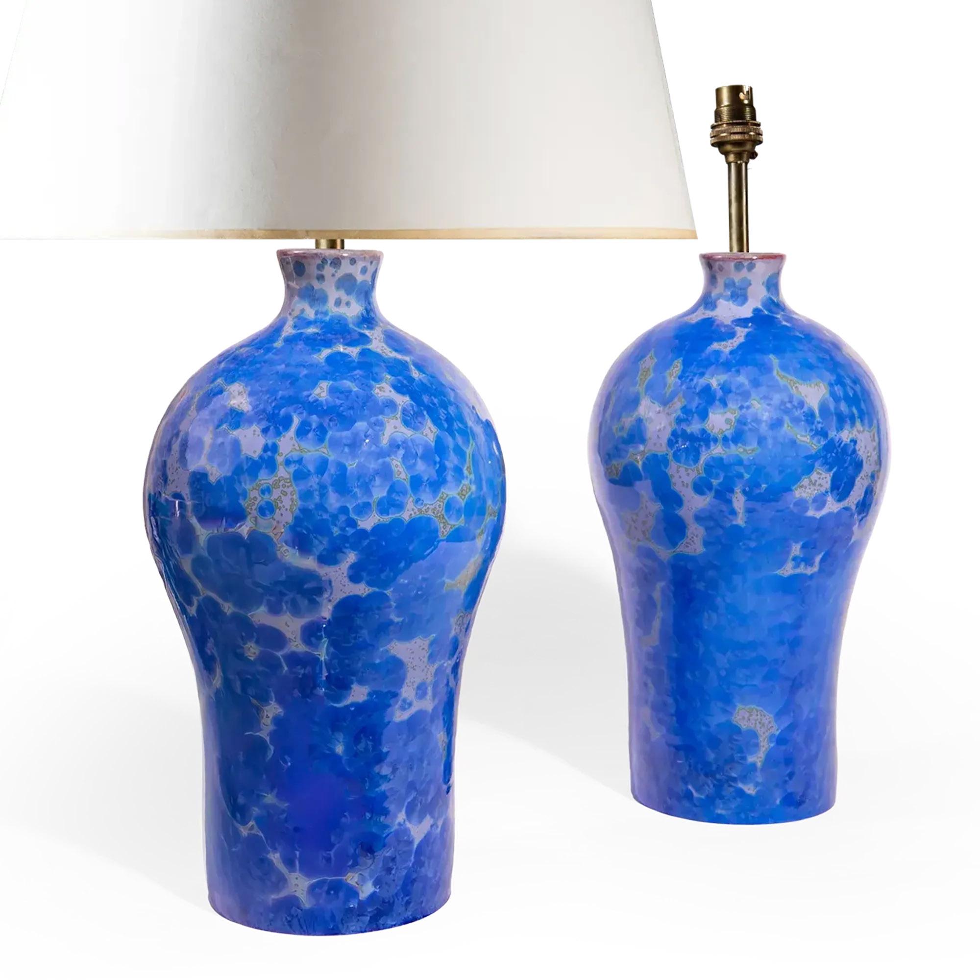 Cette élégante paire de vases en céramique, aujourd'hui utilisés comme lampes, se distingue par sa glaçure d'un bleu cristallin saisissant. La riche décoration de la surface présente des groupes de formations cristallines dans des tons vifs de