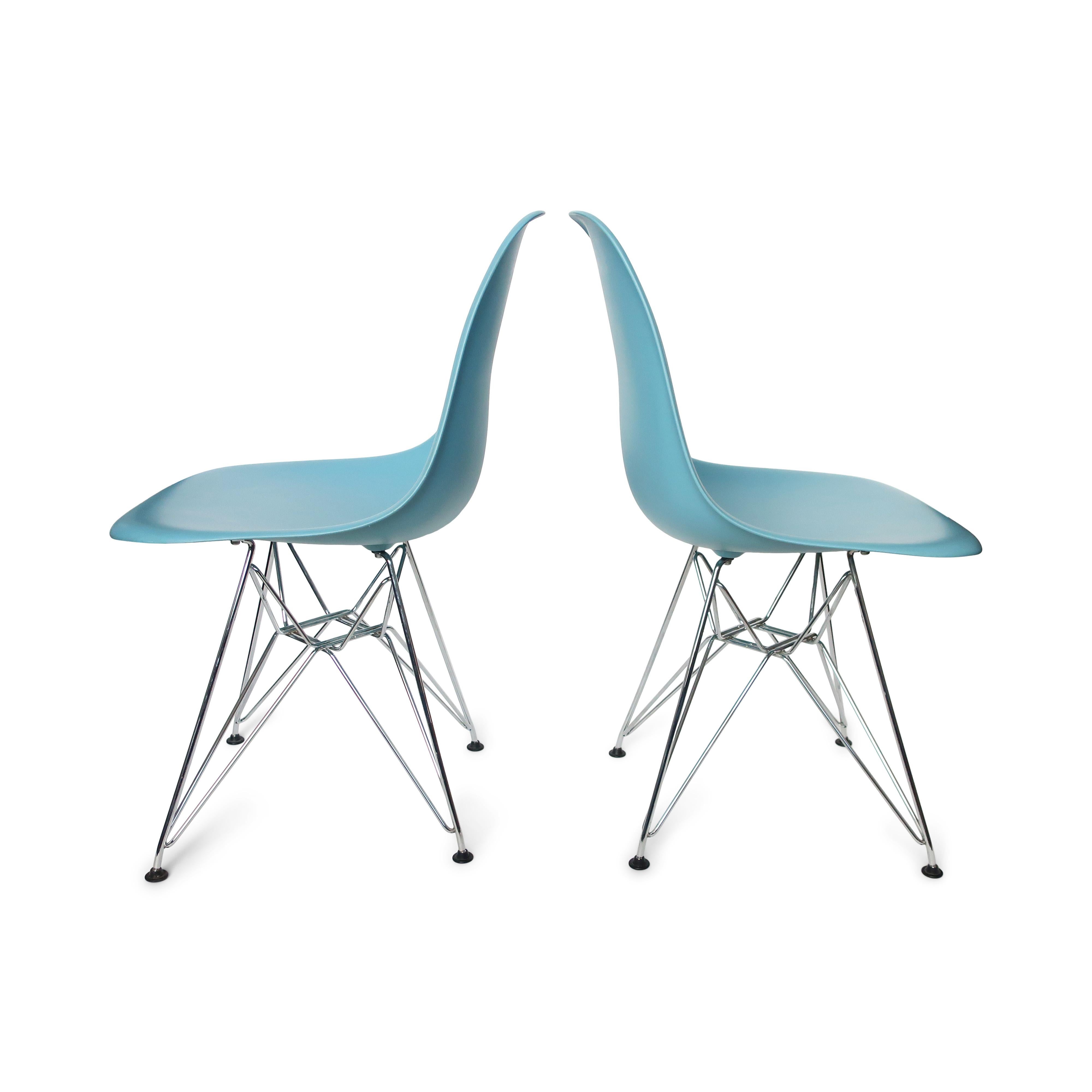 A classic pair of dining chairs designed by Ray and Charles Eames for Herman Miller. This pair was produced as part of a license agreement with Vitra. Shells are light blue with chrome Eiffel Tower bases. 

In very good vintage condition with wear