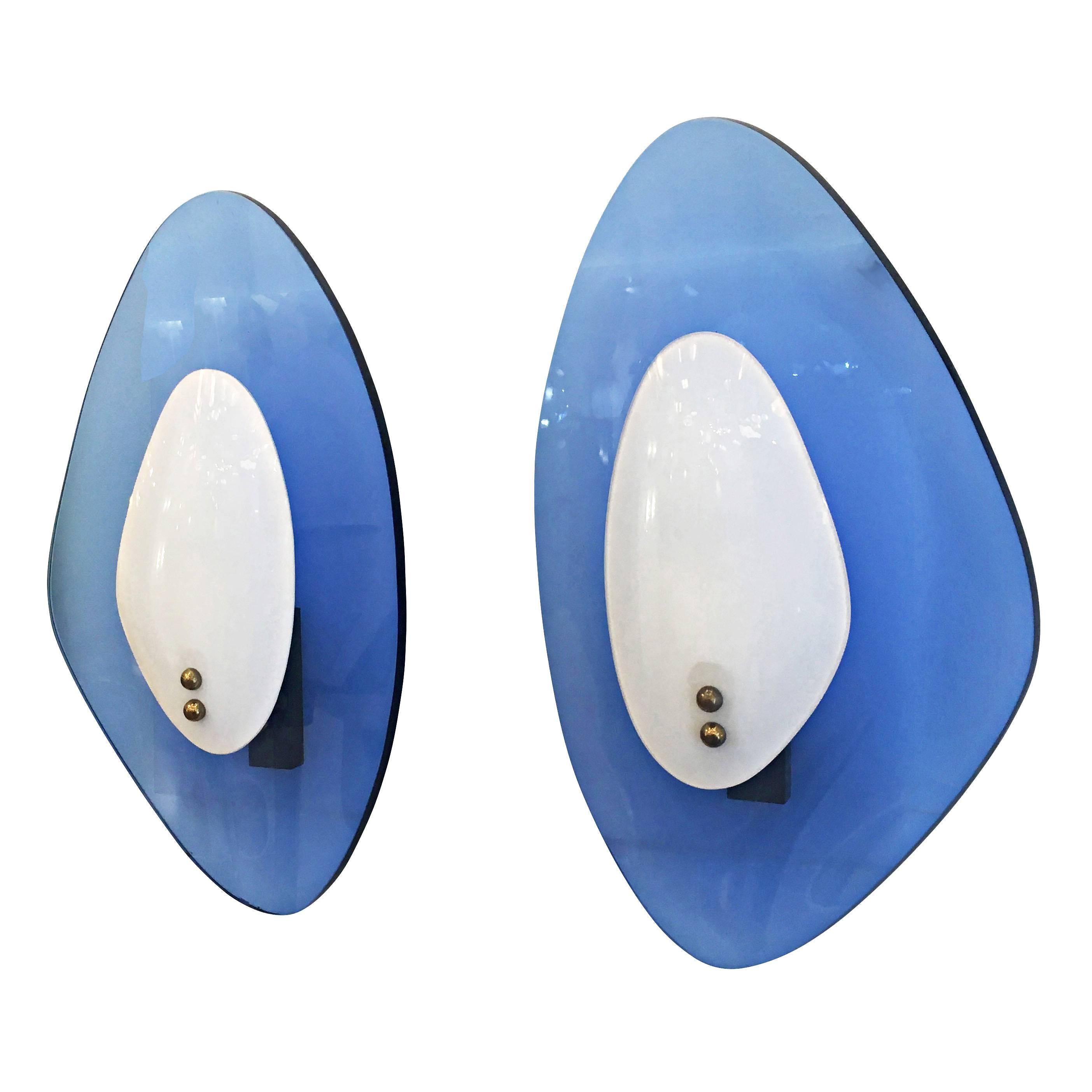 Pair of midcentury sconces by Cristal Arte composed of two contoured glass shades. The back shade is blue while the front one is white. Hardware holding one candelabra socket is brass.

Condition: Excellent vintage condition, minor wear consistent