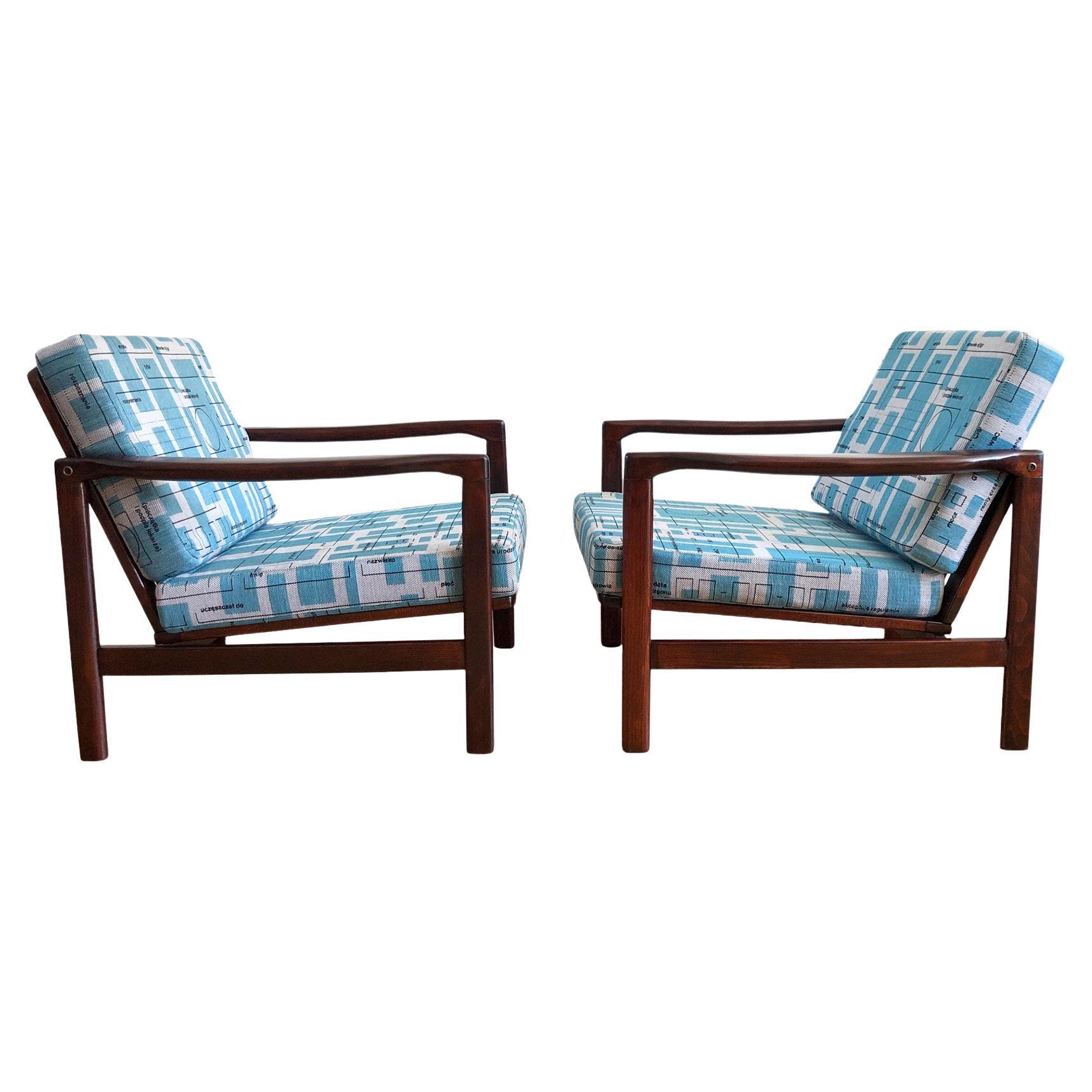 L'ensemble de deux fauteuils modèle, conçu par Zenon Baczyk, a été fabriqué par Swarzedzkie Fabryki Mebli en Pologne dans les années 1960. La structure est faite de bois de hêtre d'une couleur palissandre chaude, finie avec un vernis semi-mat. Le