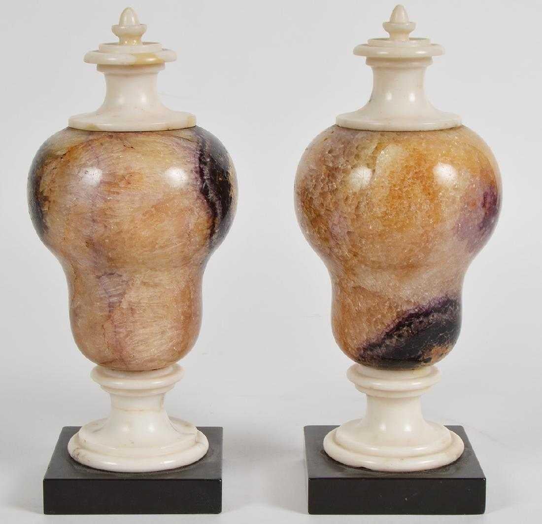 Pair of attractive blue John decorative urns, English 19th century, w. bulbous bodies in exquisite purple-blue and golden tones, with white marble finials and bases, standing on a black marble square plinth.