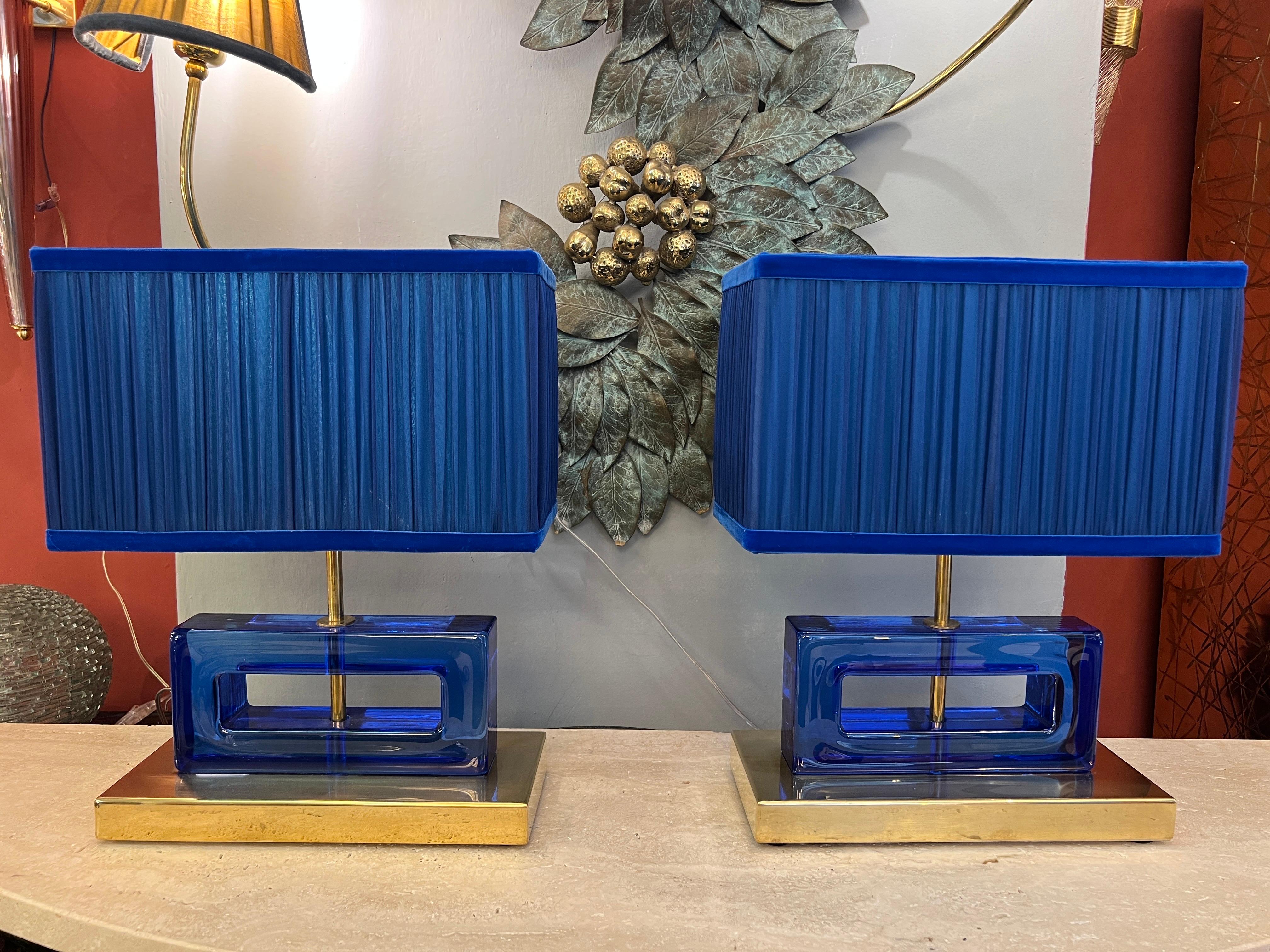 Pair of blue Murano glass blocks table lamps with brass base and our hand sewn blue lampshades.
The geometric glass blocks are solid, thick and heavy.
The double color lampshades are handmade in our internal laboratory using ruffled double color