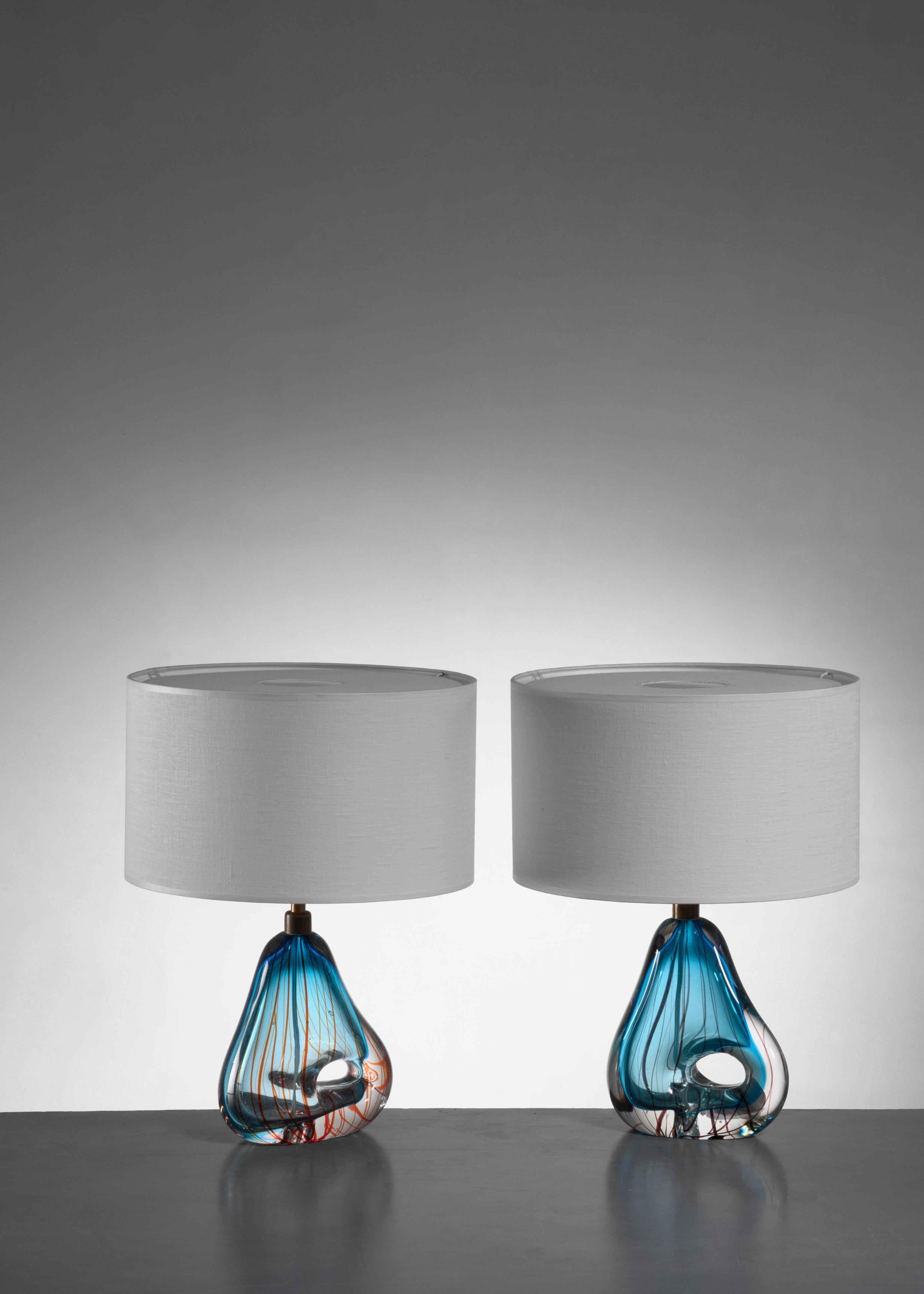 A pair of Murano glass table lamps, attributed to Dino Martens. The glass has a striped blue pattern and an opening in the base.

The measurements stated are of the lamps without a shade. The shades are newly made and other dimensions and colors
