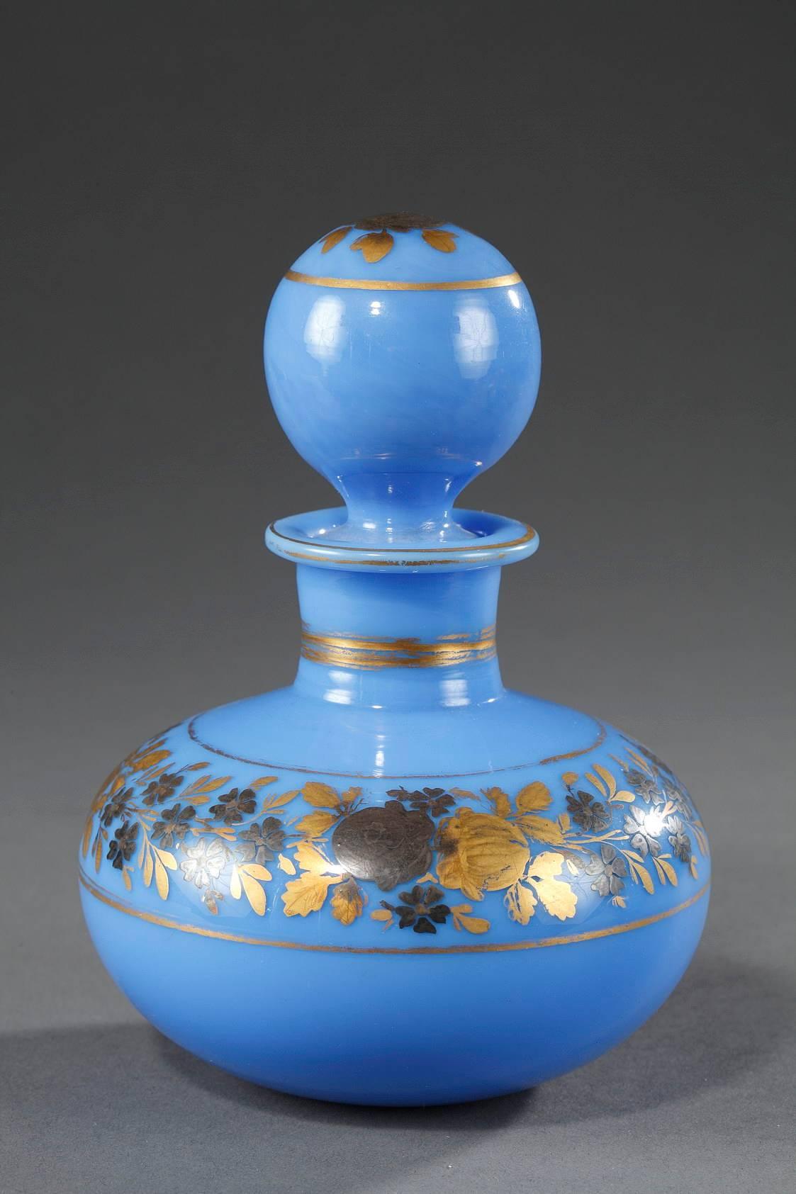 Pair of blue opaline perfume bottles with their ball-shaped stoppers. A rose and gilded petals decorates the tops of the stoppers, and gold bands highlight the necks of the bottles. Each bottle features gold bands that frame a ring of gold and dark