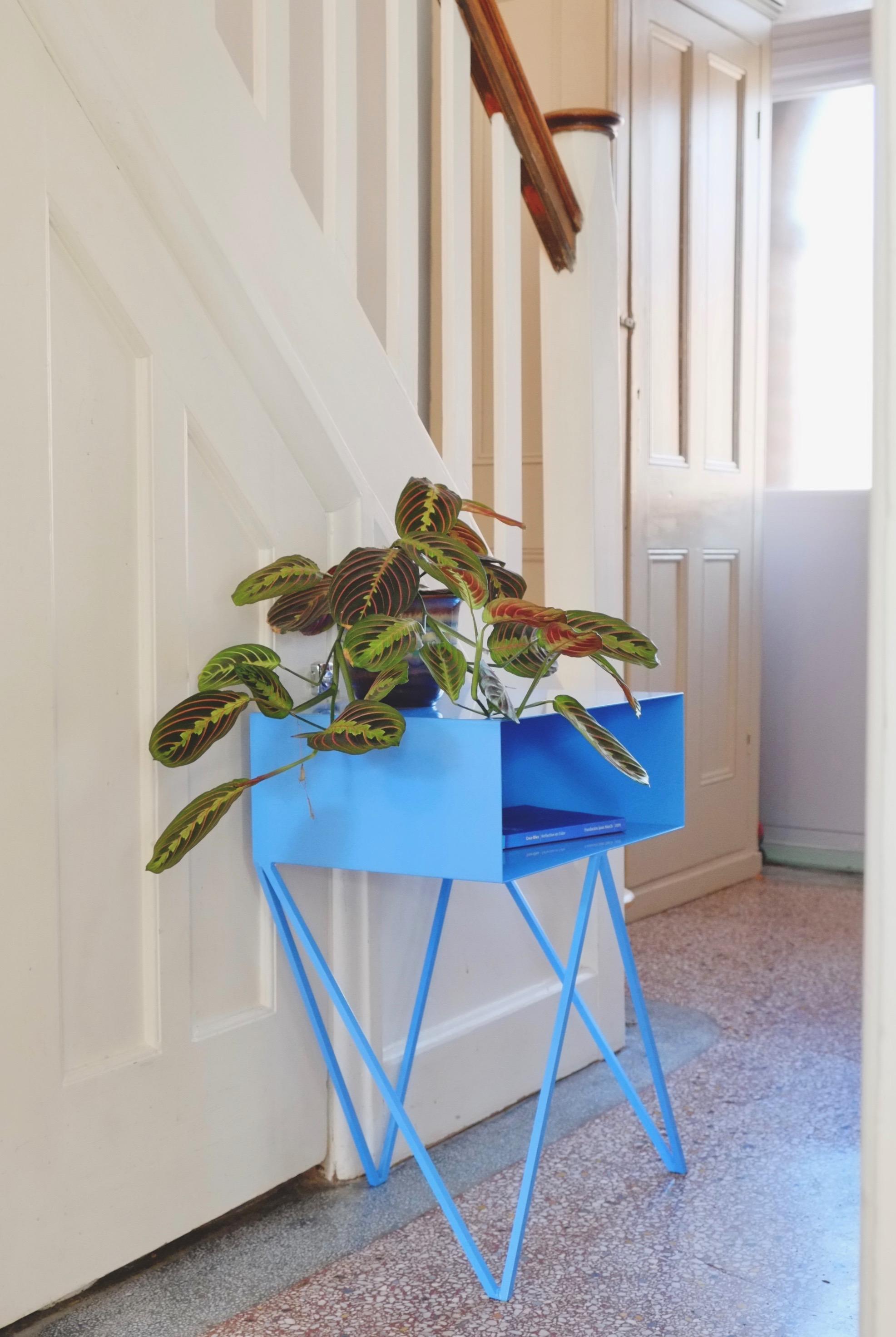 A pair of ice blue Robot bedside tables. The Robot side table features an open shelf on zig zag legs. A fun and functional design made of solid steel, powder-coated in ice blue. The clean lines look great against period details as well as in modern