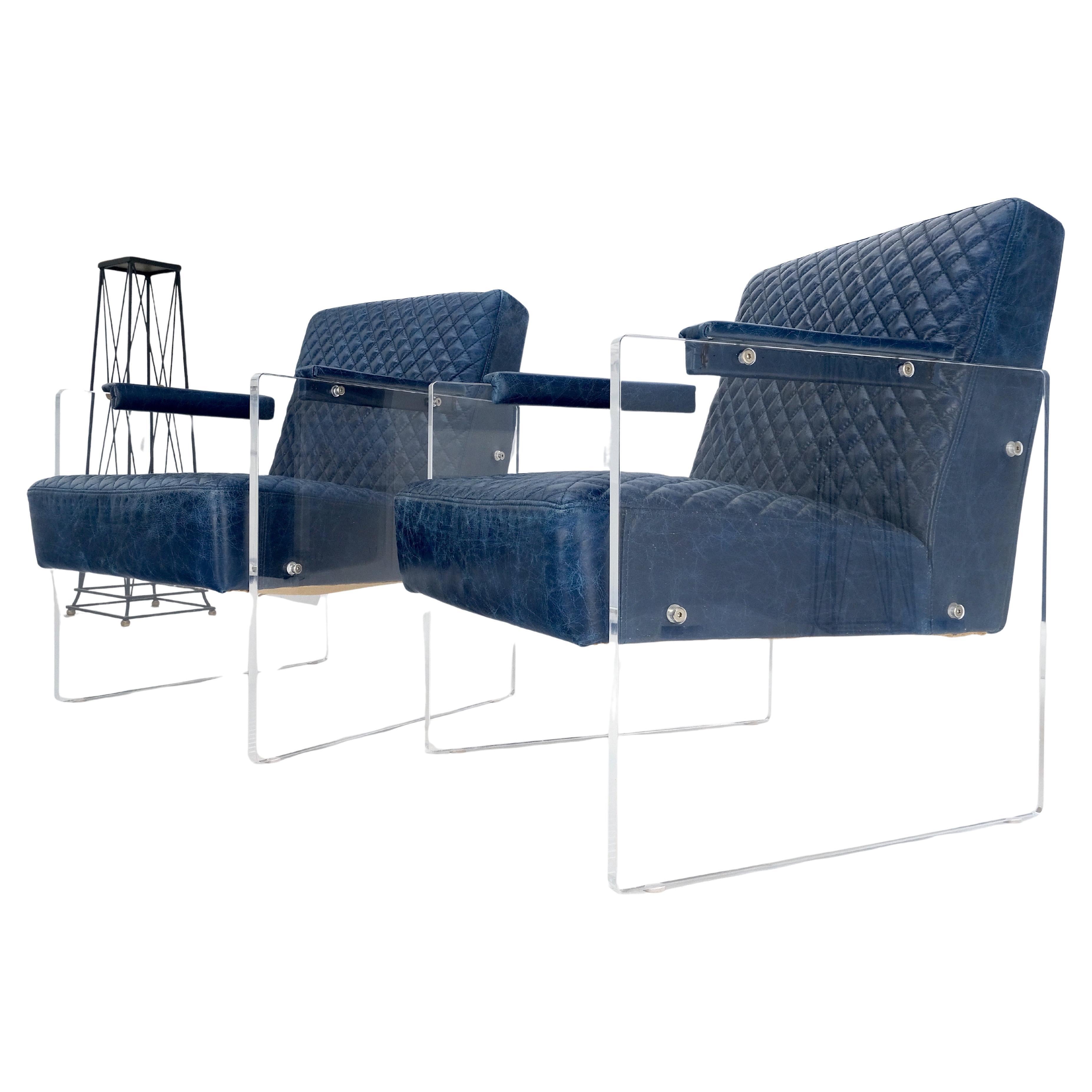 Paire de fauteuils club en cuir matelassé bleu, sièges en cuir matelassé, base en lucite, accoudoirs.