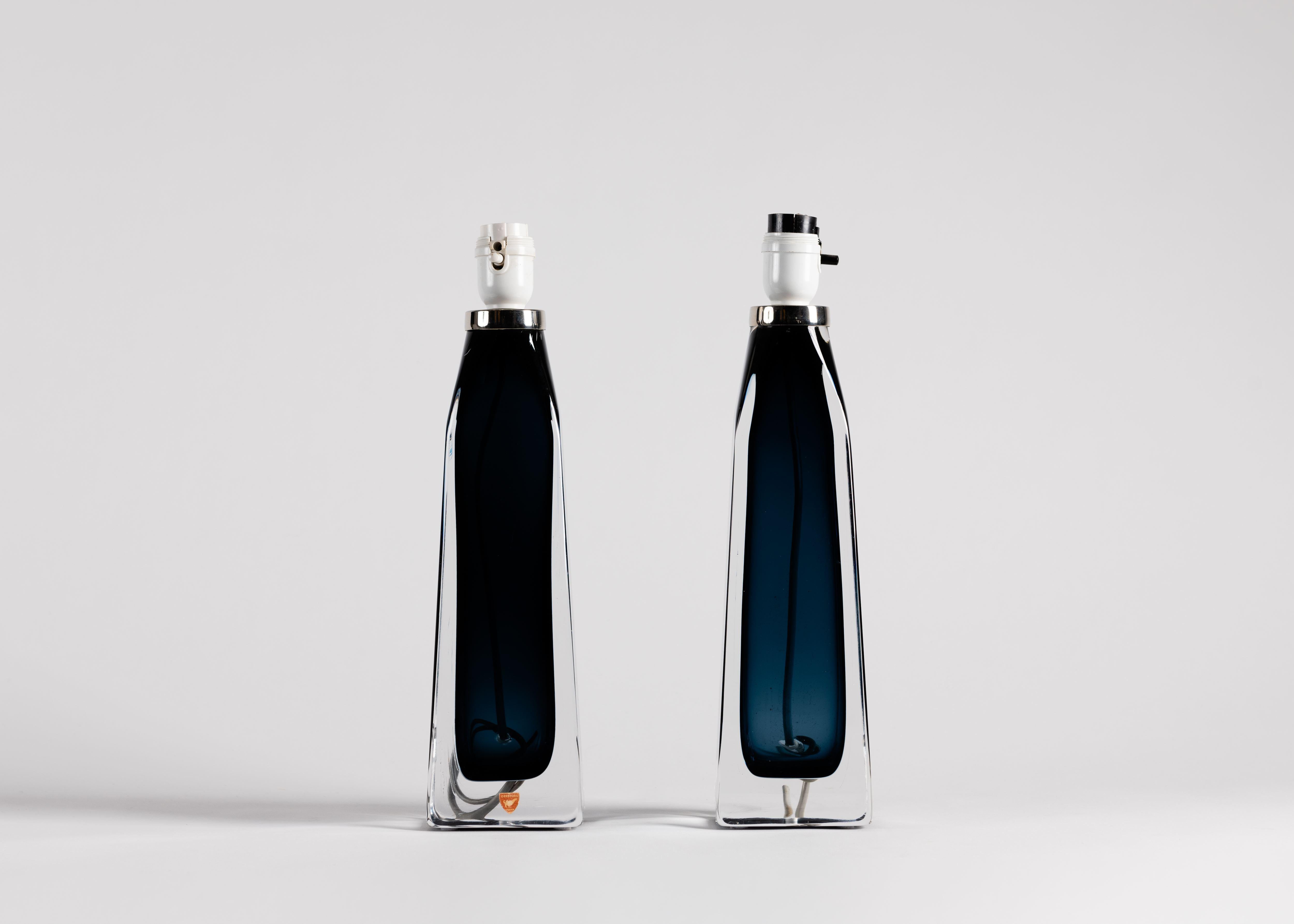 These sleek 1960s table lamps by Carl Fagerlund for Orrefors are made of glass, and contain a transparent substance that gives them their color.