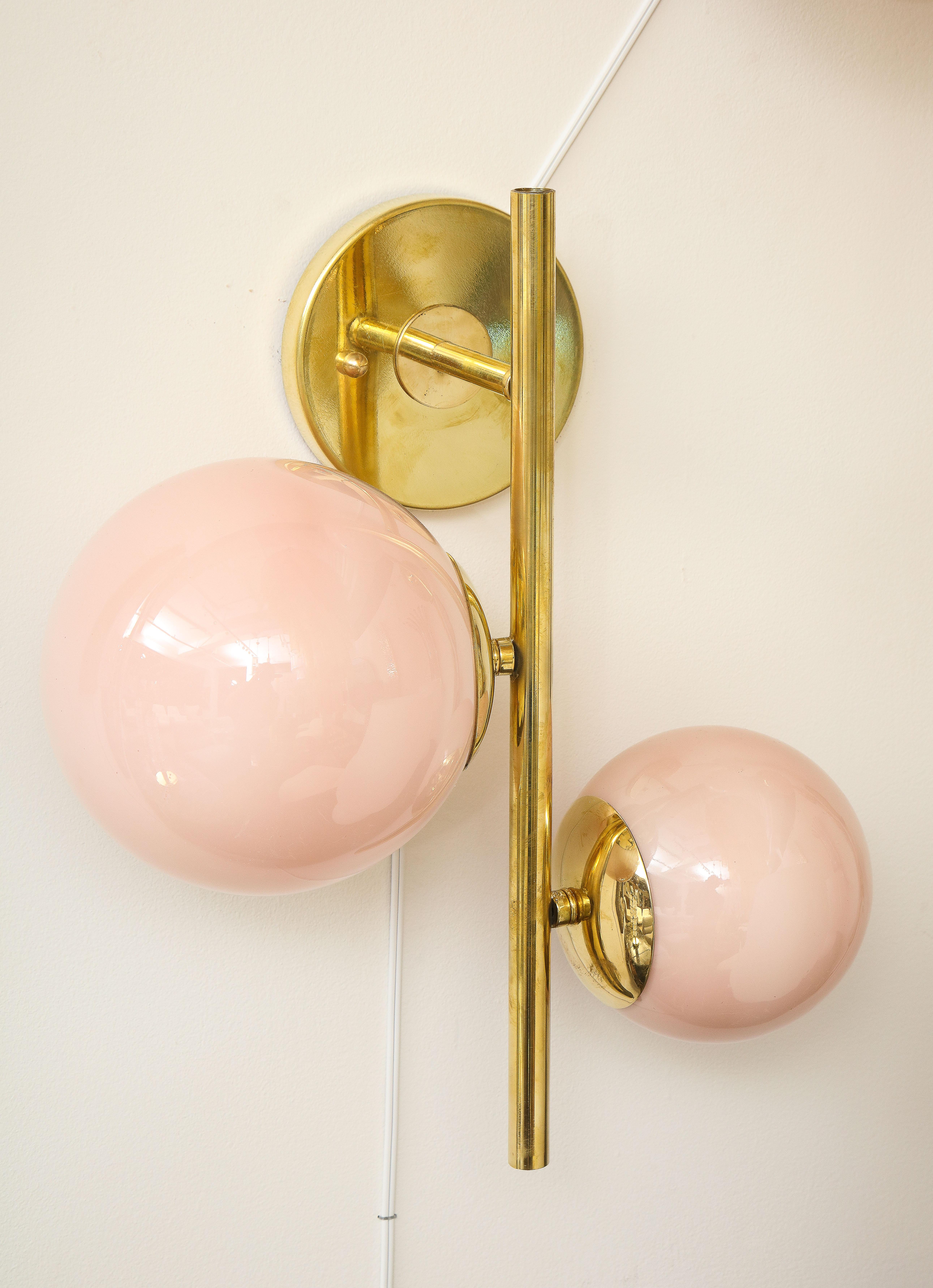 Pair of blush Pink Murano glass globes and brass sconces handcrafted in Italy, 2022. Clean lines describe this pair of linear sconces, consisting of two (2) translucent blush pink glass globes of differing diameters at different heights attached to