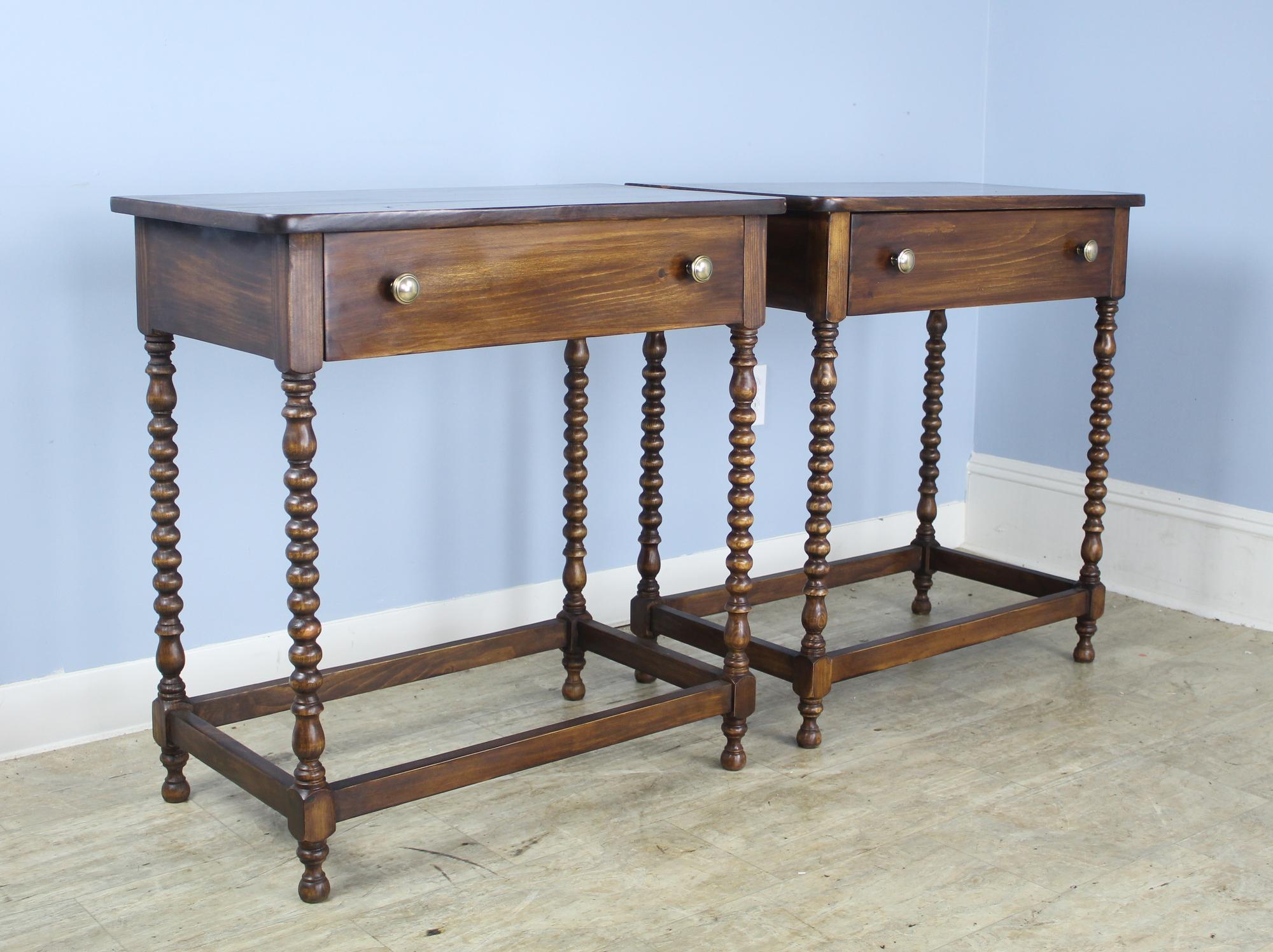 A pair of walnut side tables or nightstands with eye-catching bobbin turned legs and straight stretchers. Each table has a single roomy drawer. The tops are in good condition with lovely color and grain. Would be right on either side of a sofa or in
