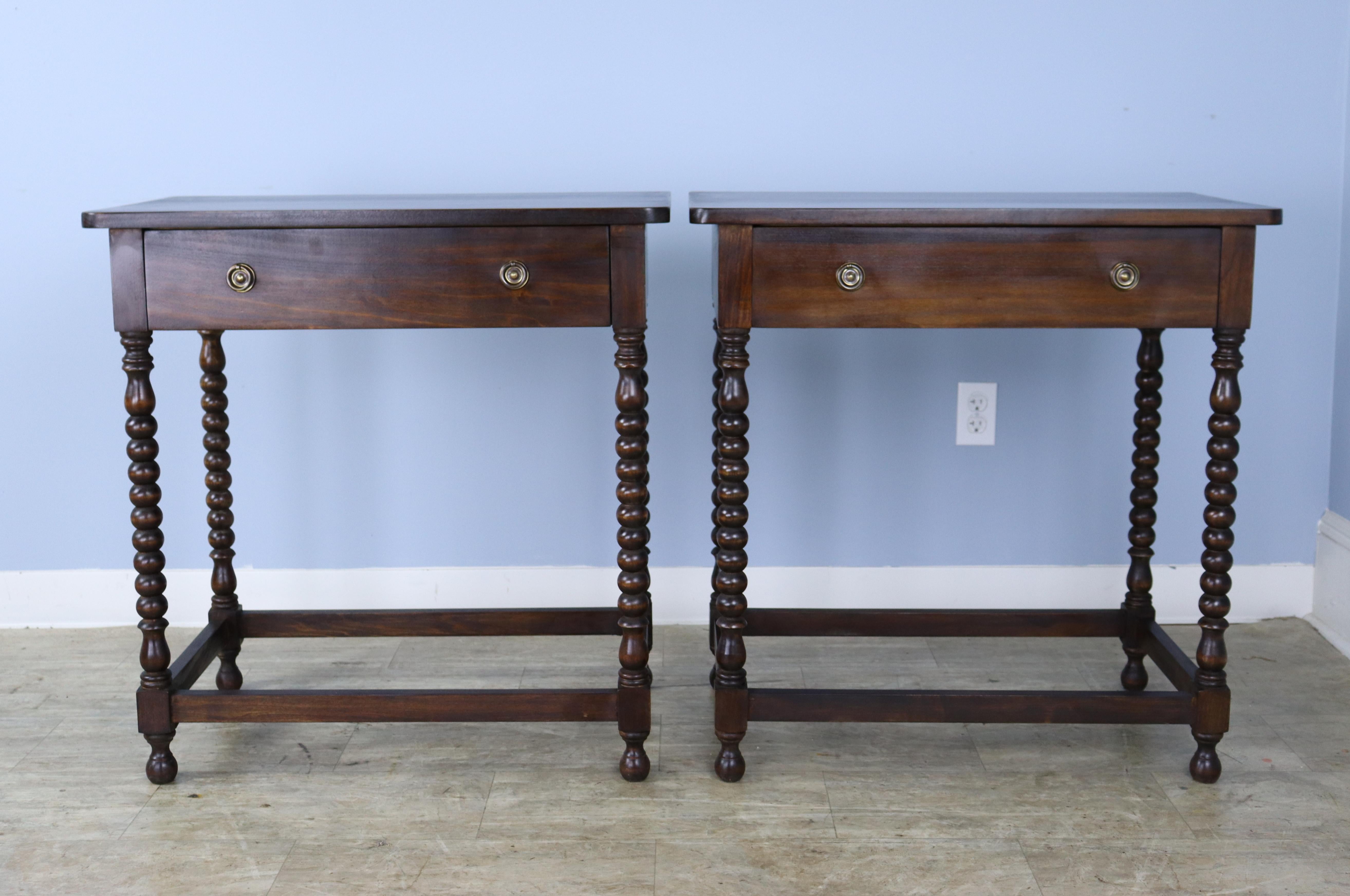 A pair of walnut side tables or nightstands with eye-catching bobbin turned legs and straight stretchers. Each table has a single roomy drawer. The tops are in good condition with lovely color and grain. Would be right on either side of a sofa or in