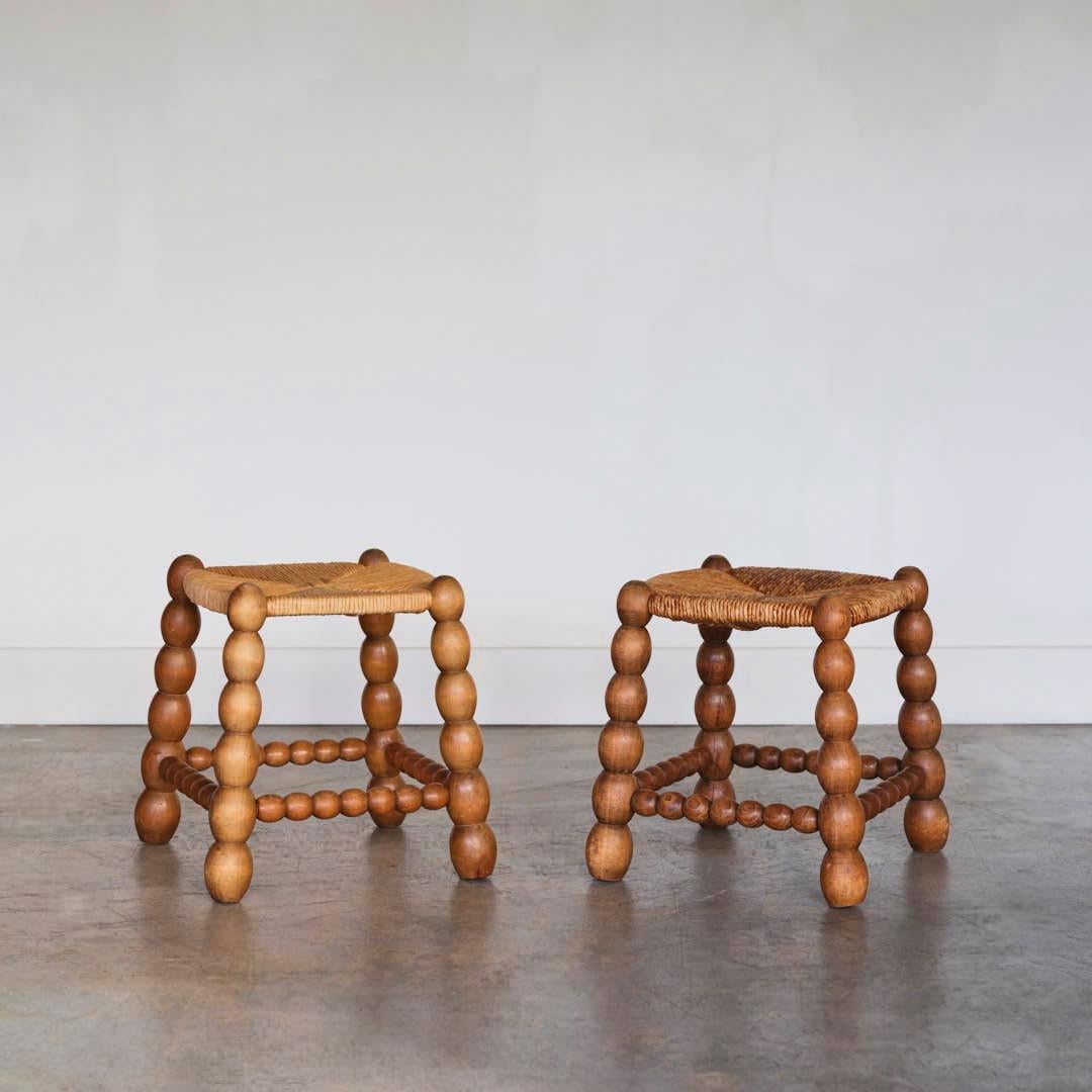 Unique pair of wood and woven stools in the style of Charles Dudouyt from France, 1940's. Carved bobbin wood legs and original woven rush seats. Original finish shows great age and patina. Sold as a pair.