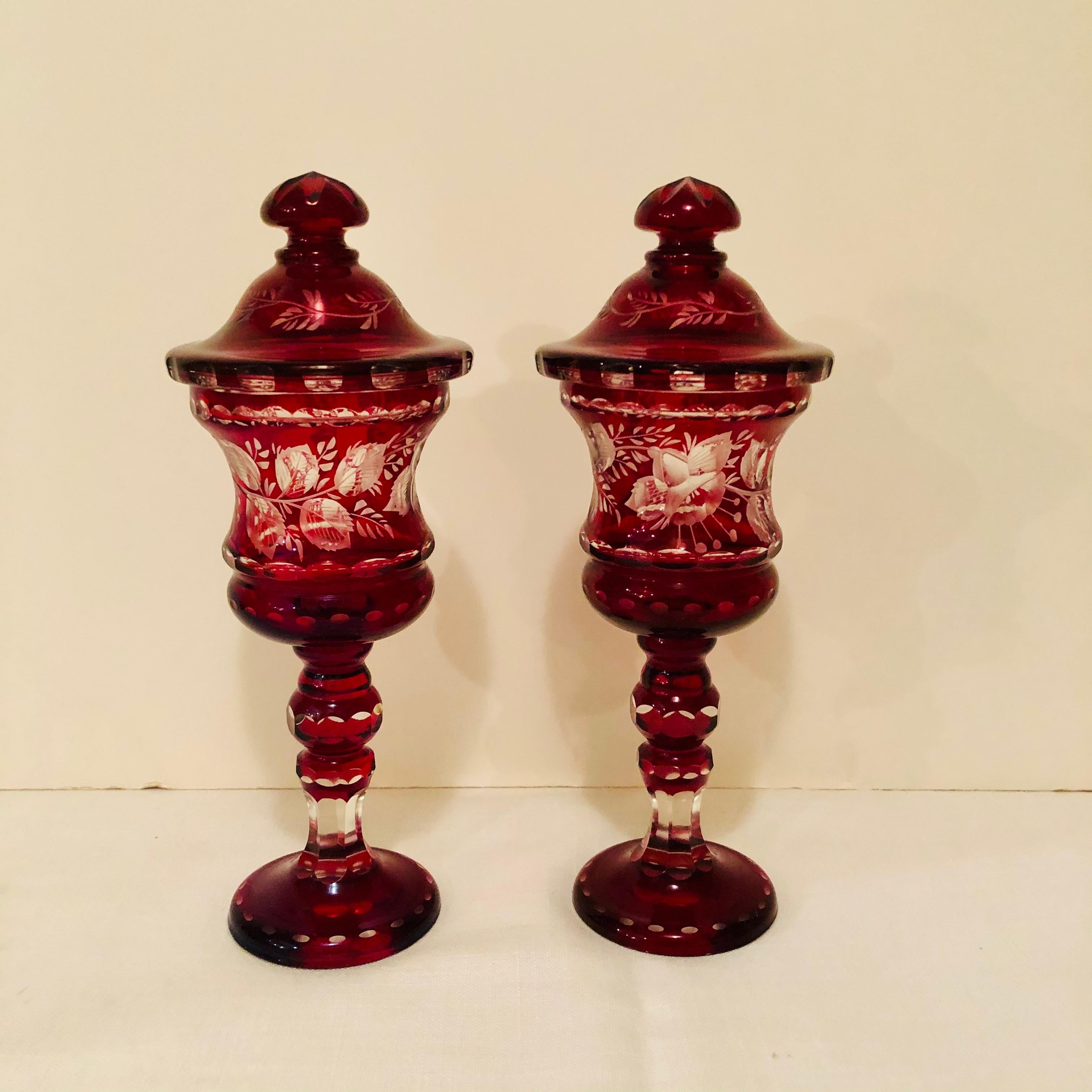 These are a stunning pair of red Bohemian covered vases with wheel cut decorations of flowers and leaves. They are 11.5 inches tall and are from circa 1900-1920. They would make a beautiful decoration on any dining room table, on a sideboard, in a