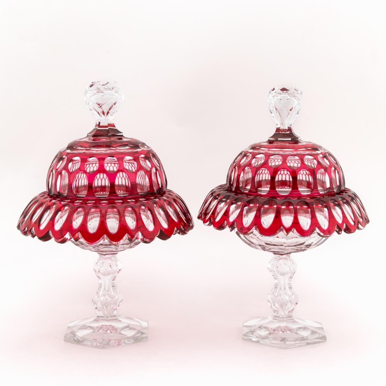 Bohemian, late 19th / early 20th century. Pair of cut to clear ruby lidded compotes in thumbprint pattern with a faceted finial on domed lid, flared and ruffled rim, and ending on a hexagonal foot. Unmarked. 
Approx. h. 11.25