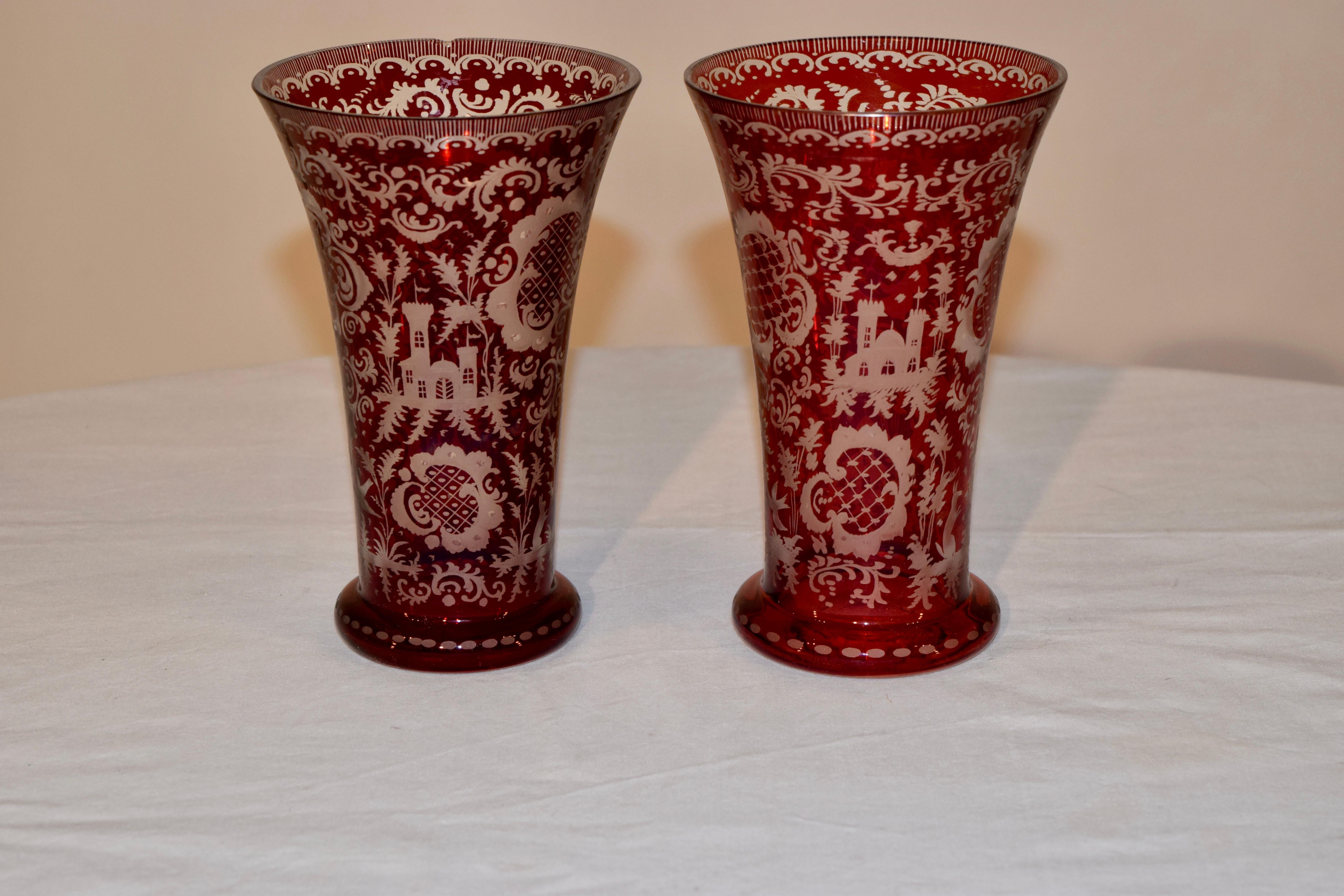 Pair of Bohemian flash cut cranberry to clear cut glass vases with scenes of castles, deer and fauna. Highly decorative. One small repair to rim, which is photographed. The bases measure 3.5