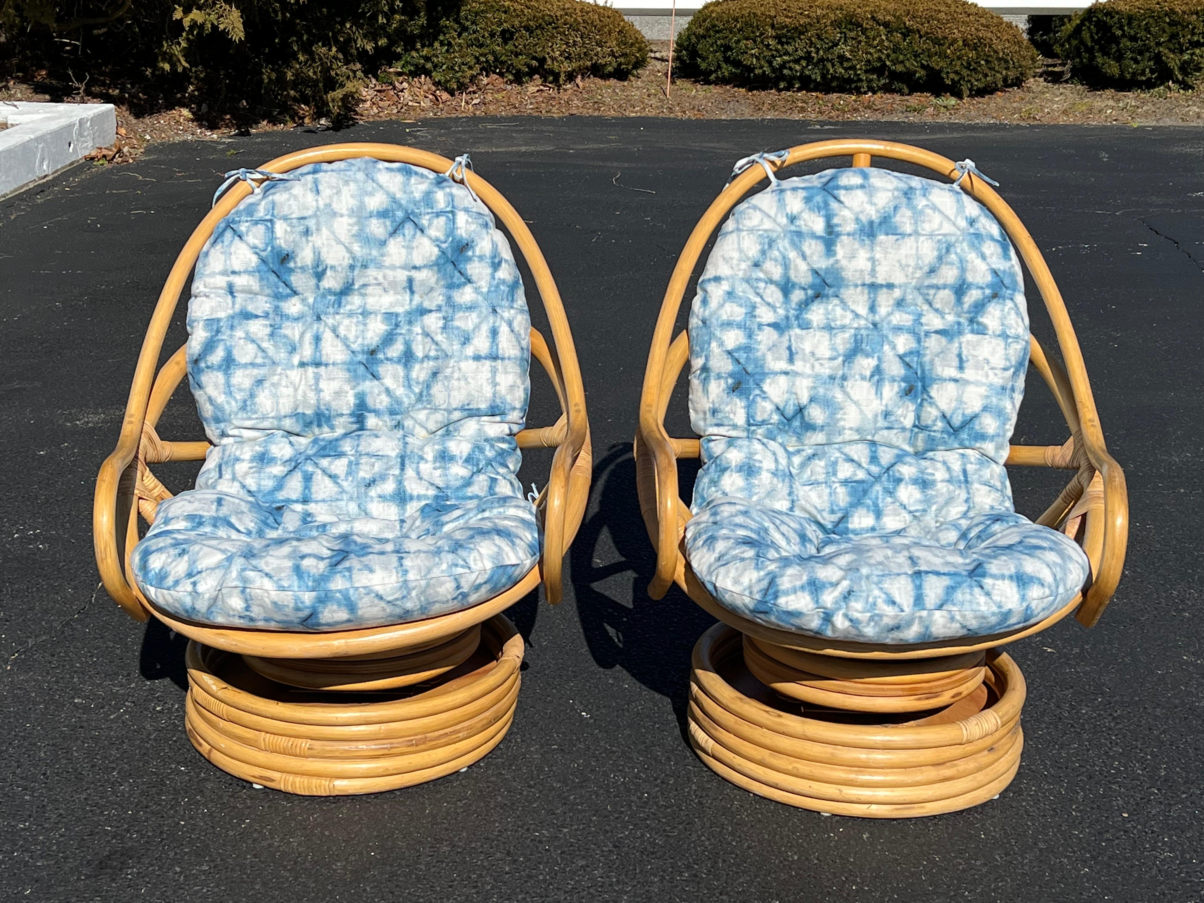 Pair of Boho Rattan Bamboo swivel saucer chairs in the style of Paul Frankl.
 Classic pair of Mama San cocoon chairs  with custom made cushions. New cushions are a weather treated Shibori fabric. Classic coastal look and feel with fabulous saucer
