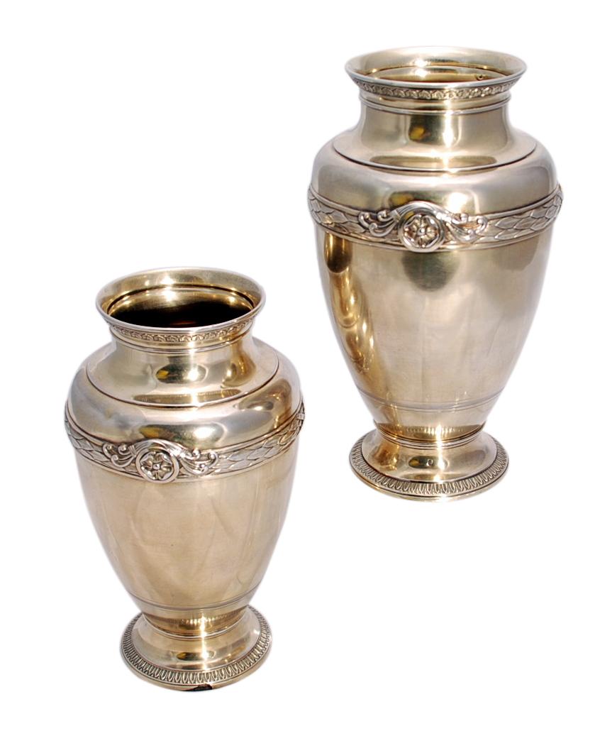 Pair of French silver gilt vases in urn form, by Boin-Taburet, a Parisian silversmith, from the early 20th century in Louis XVI style. The spreading circular bases have a leaf-tip borders and the body is applied with a band of ribbon-wrapped foliage