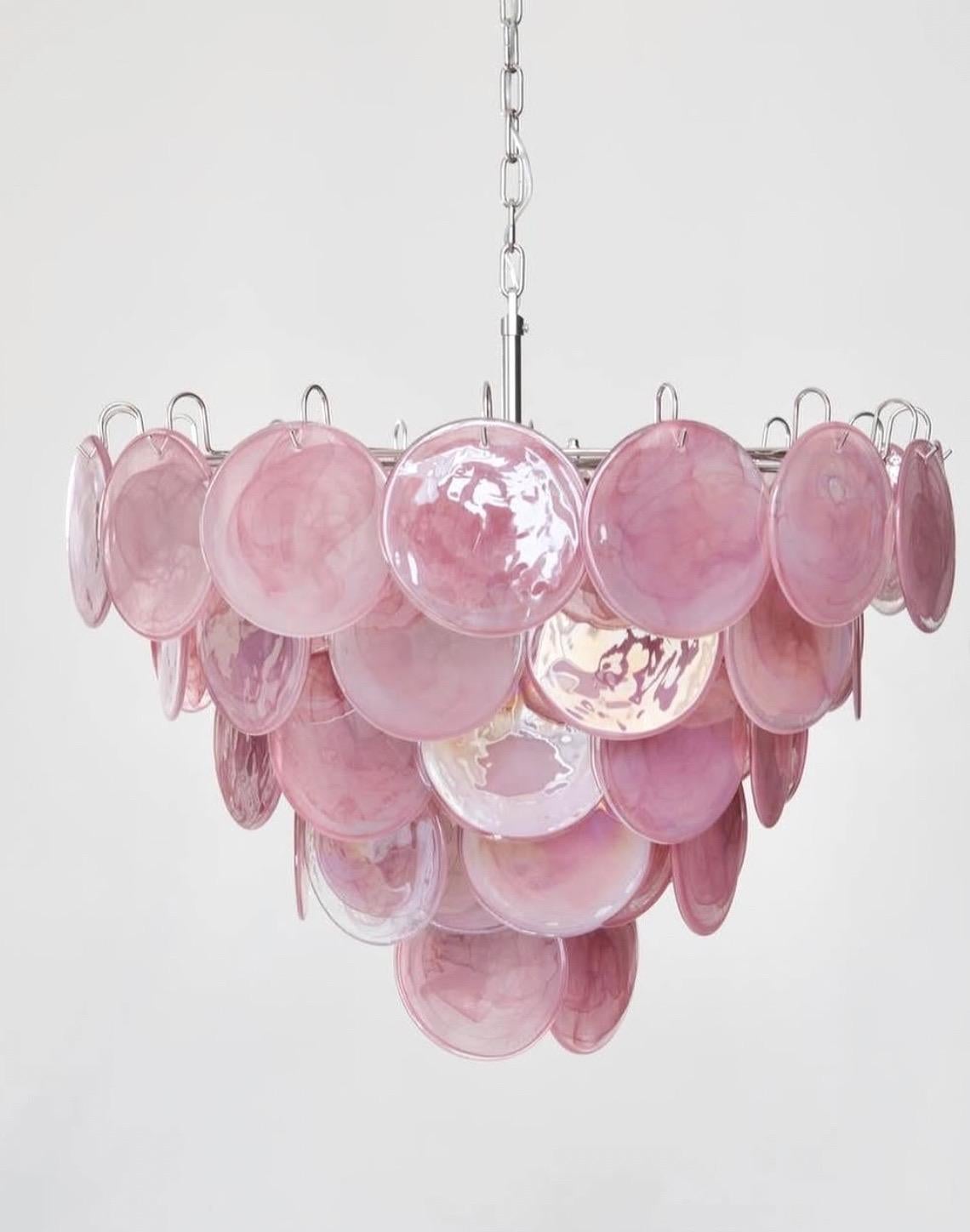 Paire de lustres éclectiques en verre coloré de Murano en rose. Chaque lustre comporte 57 disques roses dans le style Vistosi. Les disques de verre présentent un magnifique motif tourbillonnant dans différentes nuances de rose. Les lunettes sont