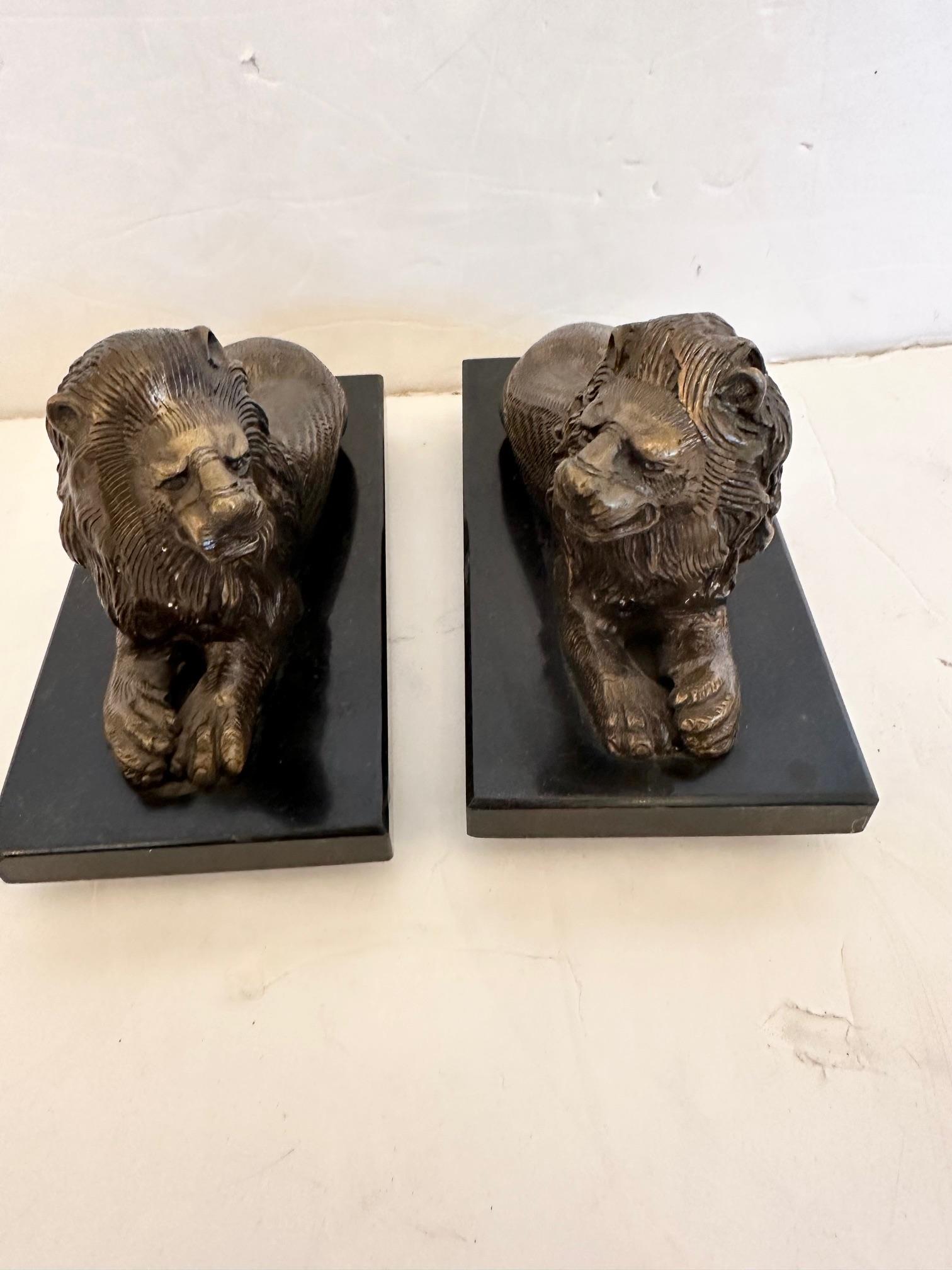 Handsome pair of bookends or desk accessories having recumbent bronze lions on belgian slate bases.