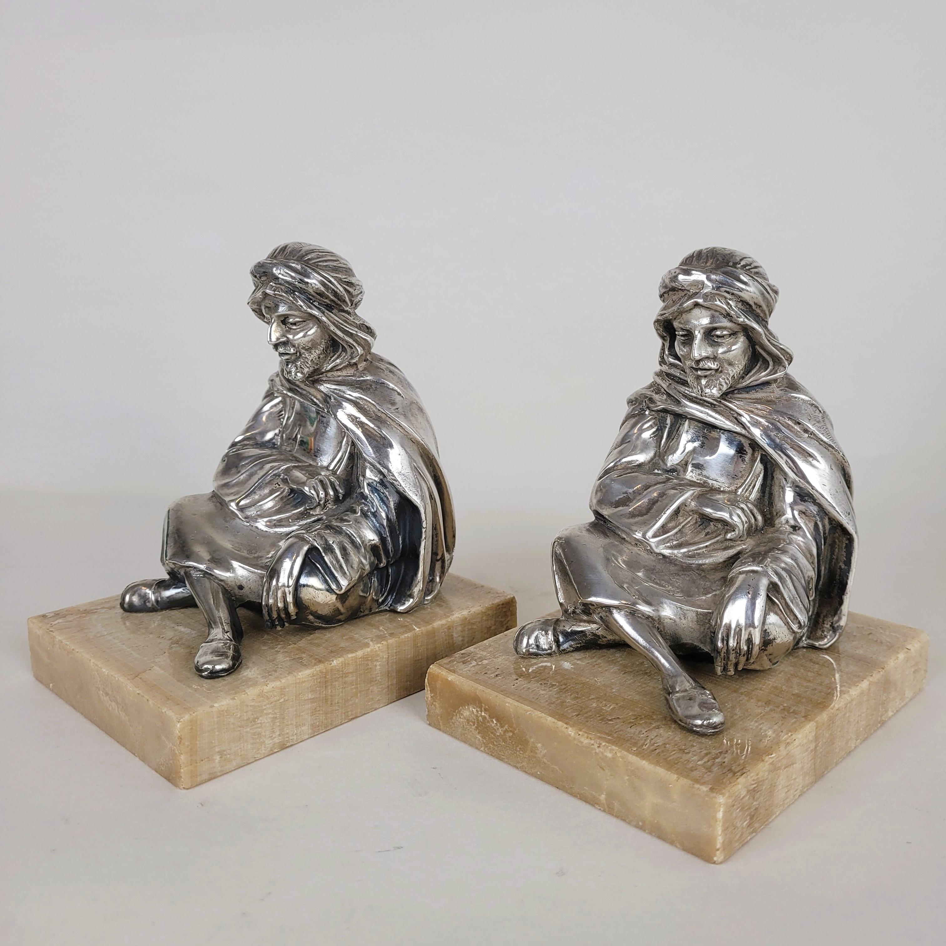 Paire de serre-livres représentant des orientaux assis, enveloppés dans leurs écharpes.

Figures en métal argenté, sur une base en onyx

Bon état général, petits éclats sur le marbre

Hauteur 13.5 cm
9.5 x 12.5 cm