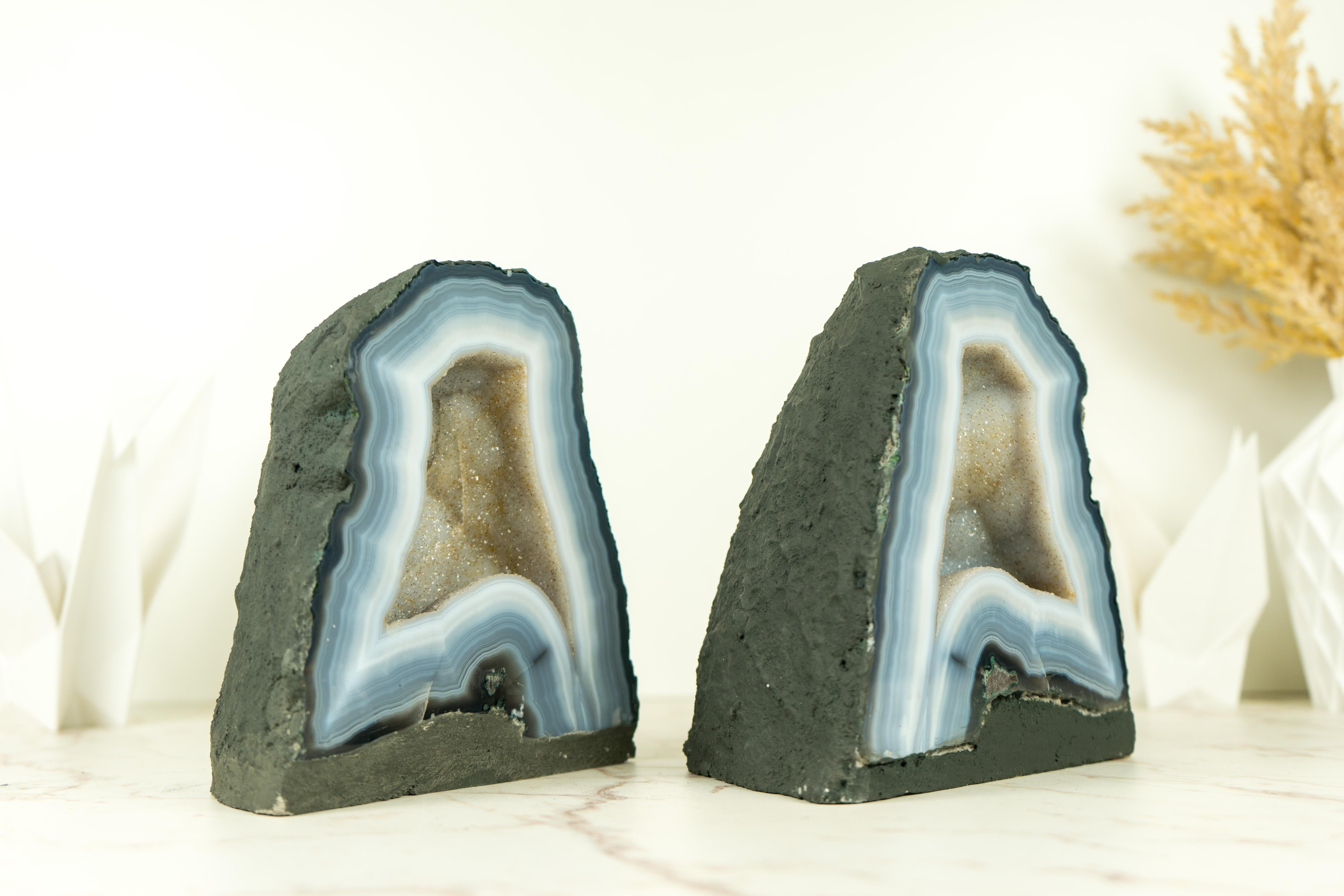 Small yet stunning, this pair of Bookmatching Blue and White Lace Agate Geodes brings numerous flawless natural agate laces, along with sparkly white galaxy crystals that form the beautiful aesthetics of the pair. It's undoubtedly of standout