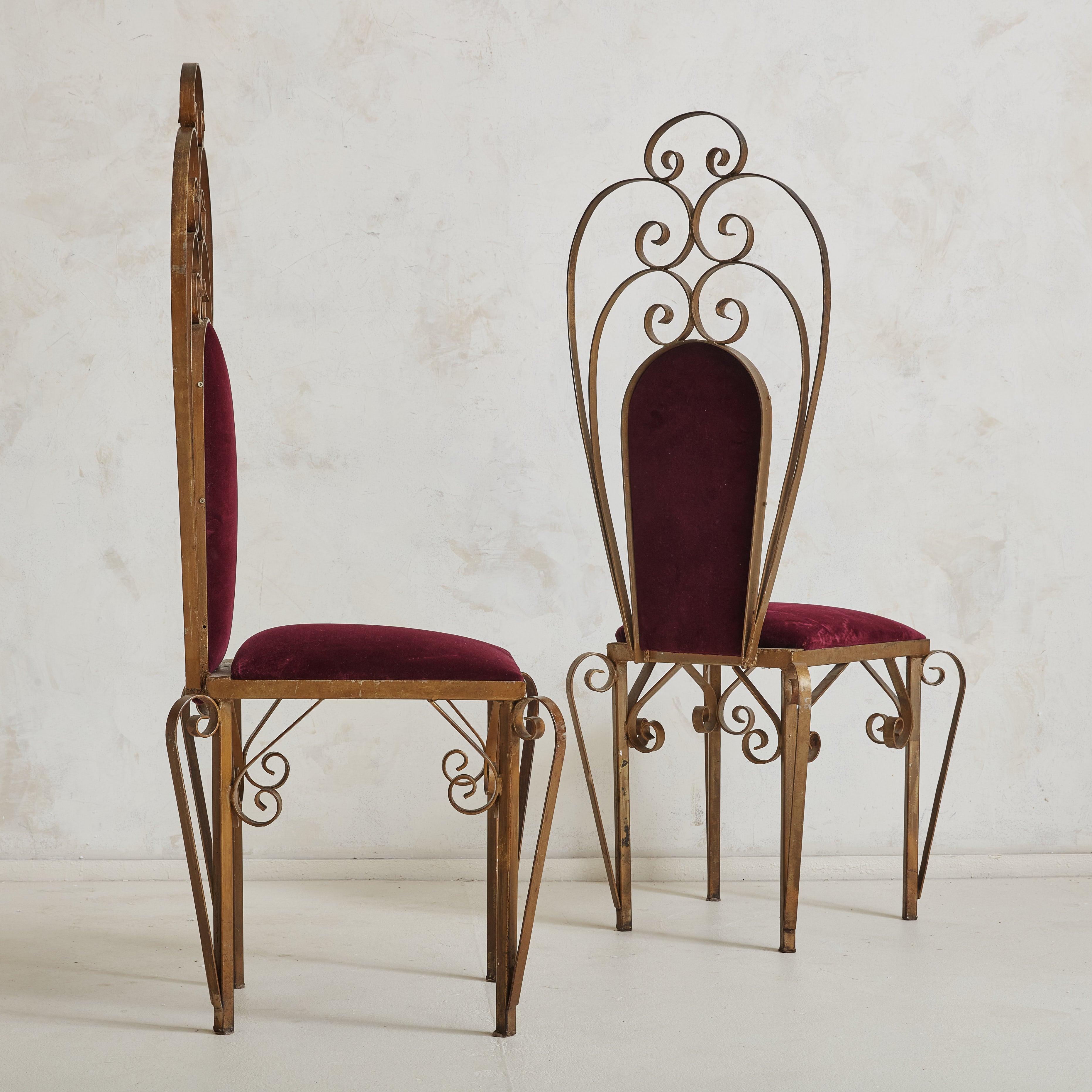 A pair of vintage sculptural side chairs featuring intricate gilded iron frames with high backs and elegant scroll motifs. Rich, bordeaux hued velvet upholstery beautifully complements the natural patina along the frames. 20th Century.

Condition: