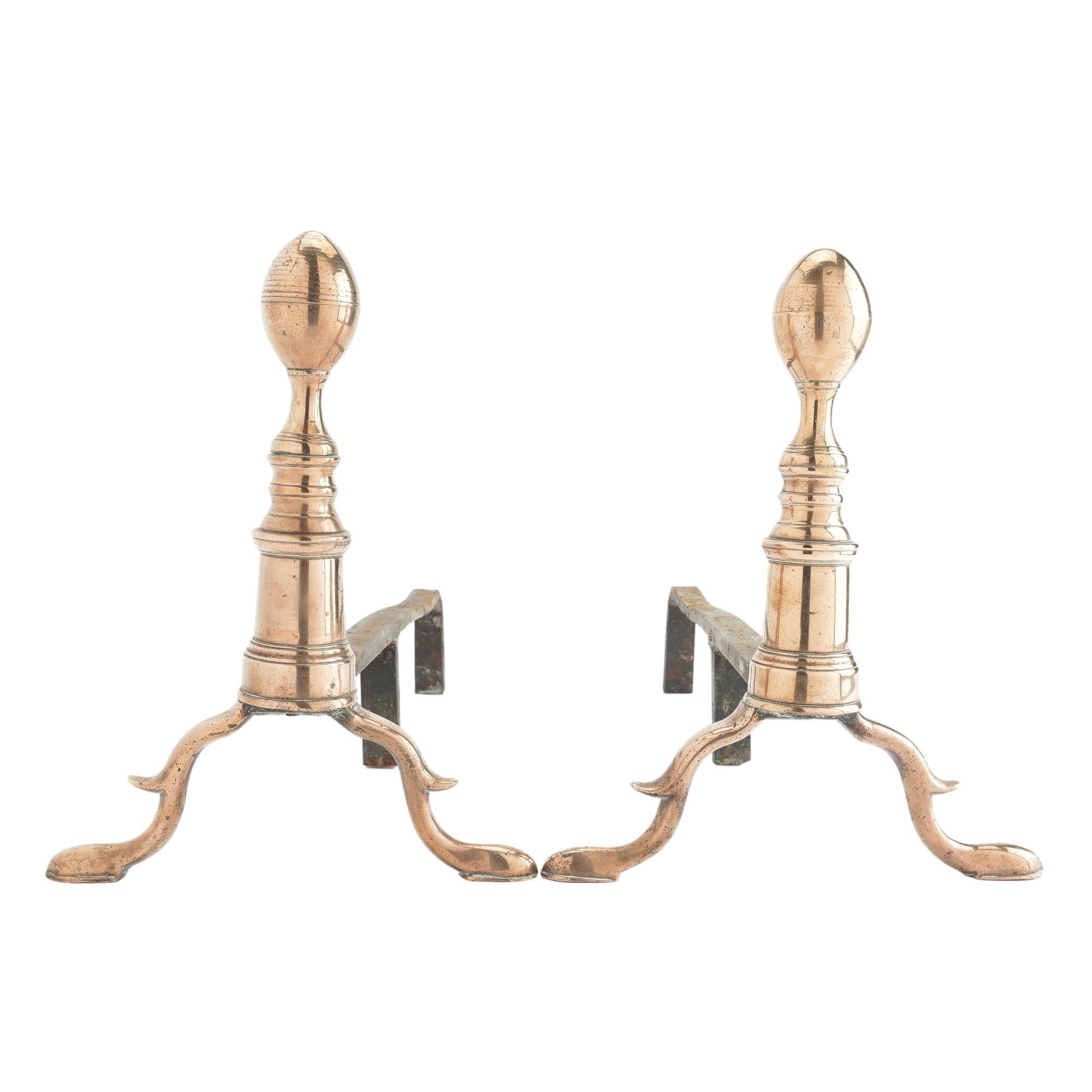 Pair of American cast bell metal brass lemon top andirons. The fire dog balusters are cast in three parts with an oval lemon form finial on waisted pedestal atop a doric column on a square plinth. The arched legs with spurs rest on refined slipper
