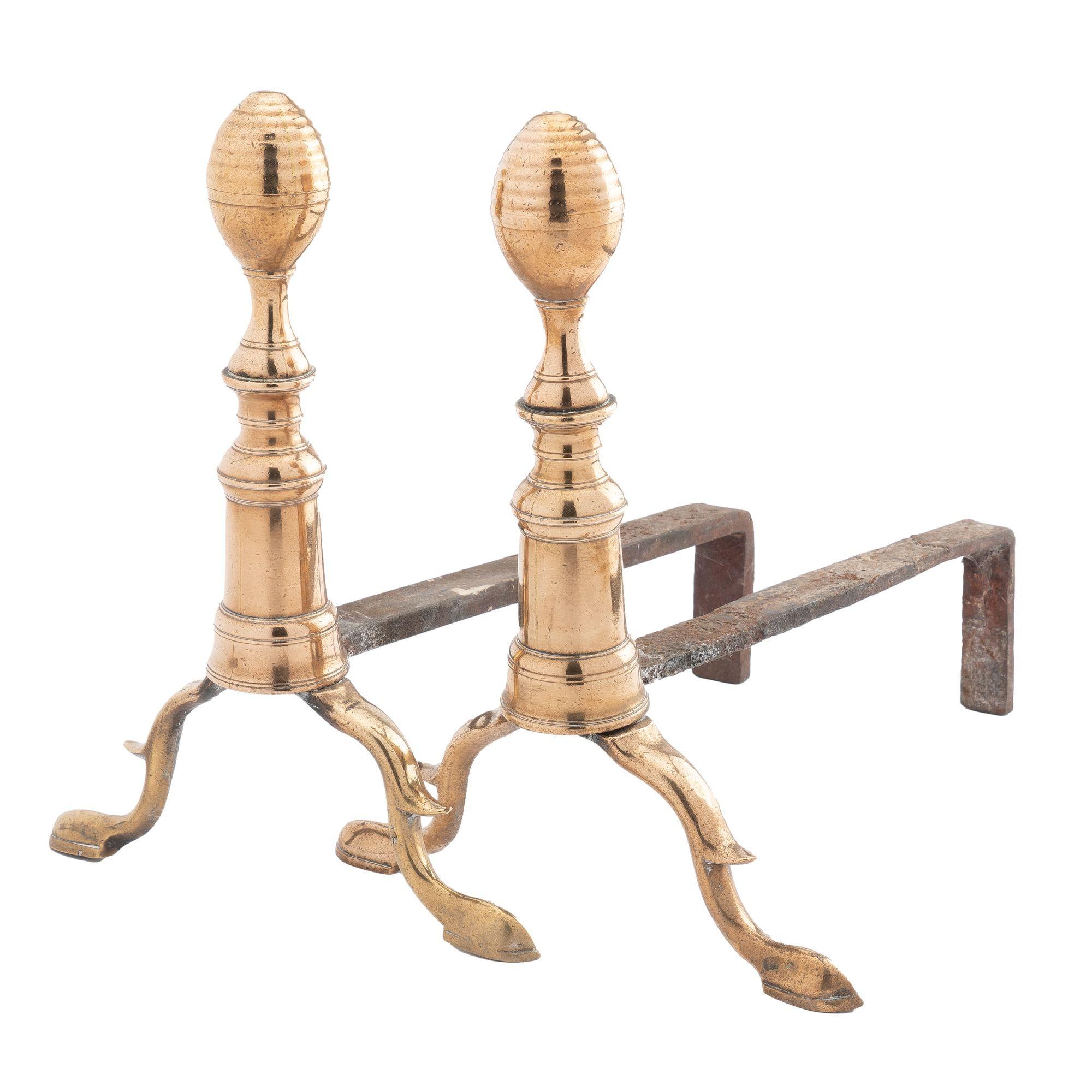 Pair of cast brass half beehive fluted lemon top andirons on turned pedestal & arched spurred legs with slipper feet. The brass is peened to a forged iron log rest and supported by an angled leg.
American, Boston, circa 1790.