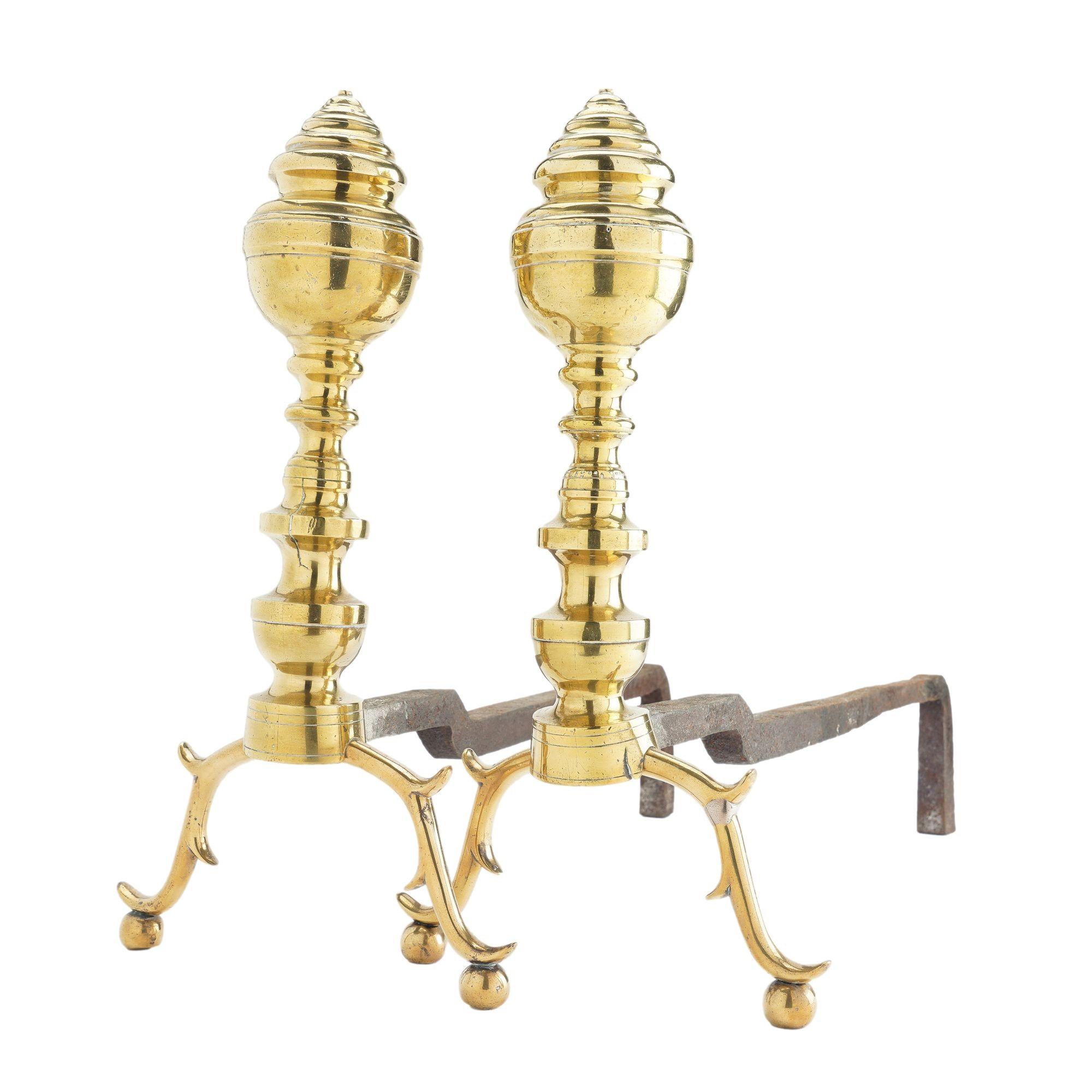Pair of generously proportioned American cast brass beehive andirons with arched spur legs on ball feet. The brass castings support a forged iron log rest.

Boston, circa 1815-25.