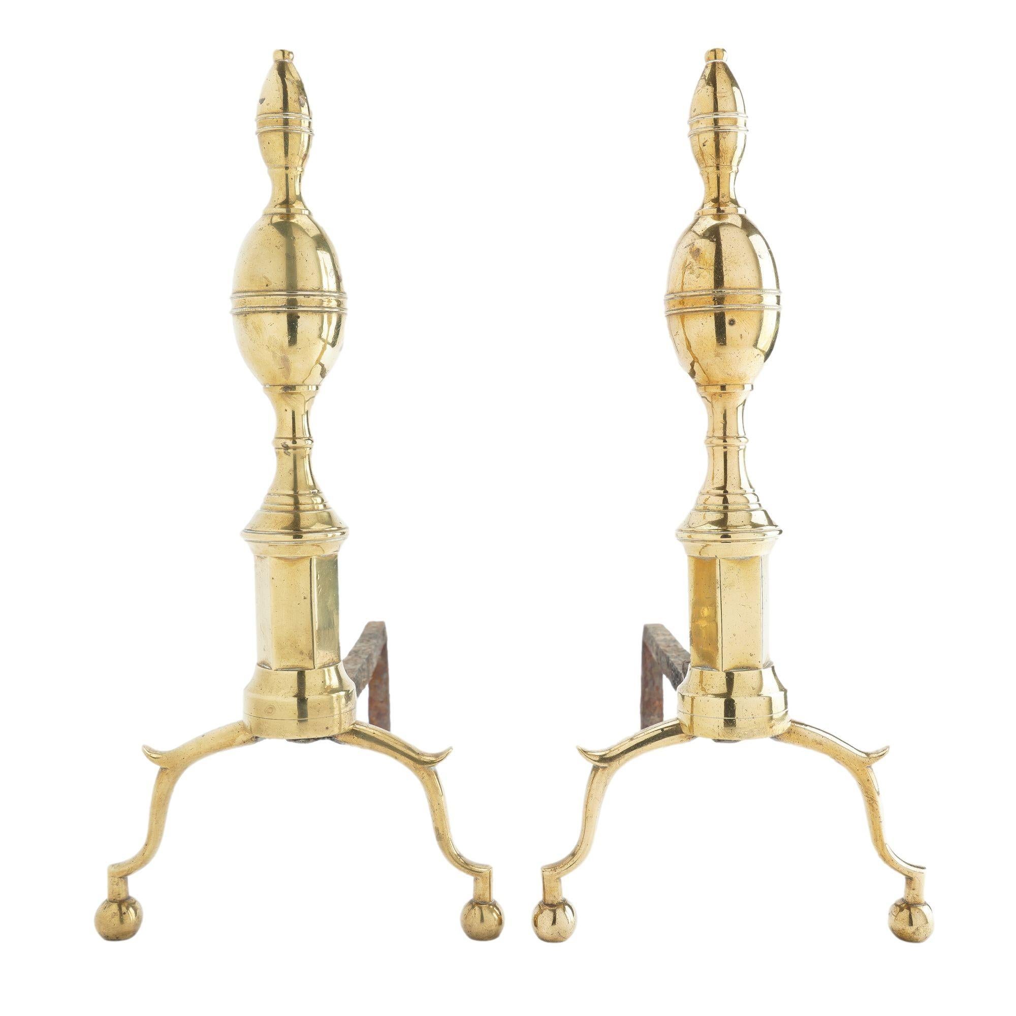 Pair of American cast brass double lemon top andirons on pillar plinth with arched, spurred legs on ball feet, and supported by a forged iron log rest.
American, Boston, circa 1790.