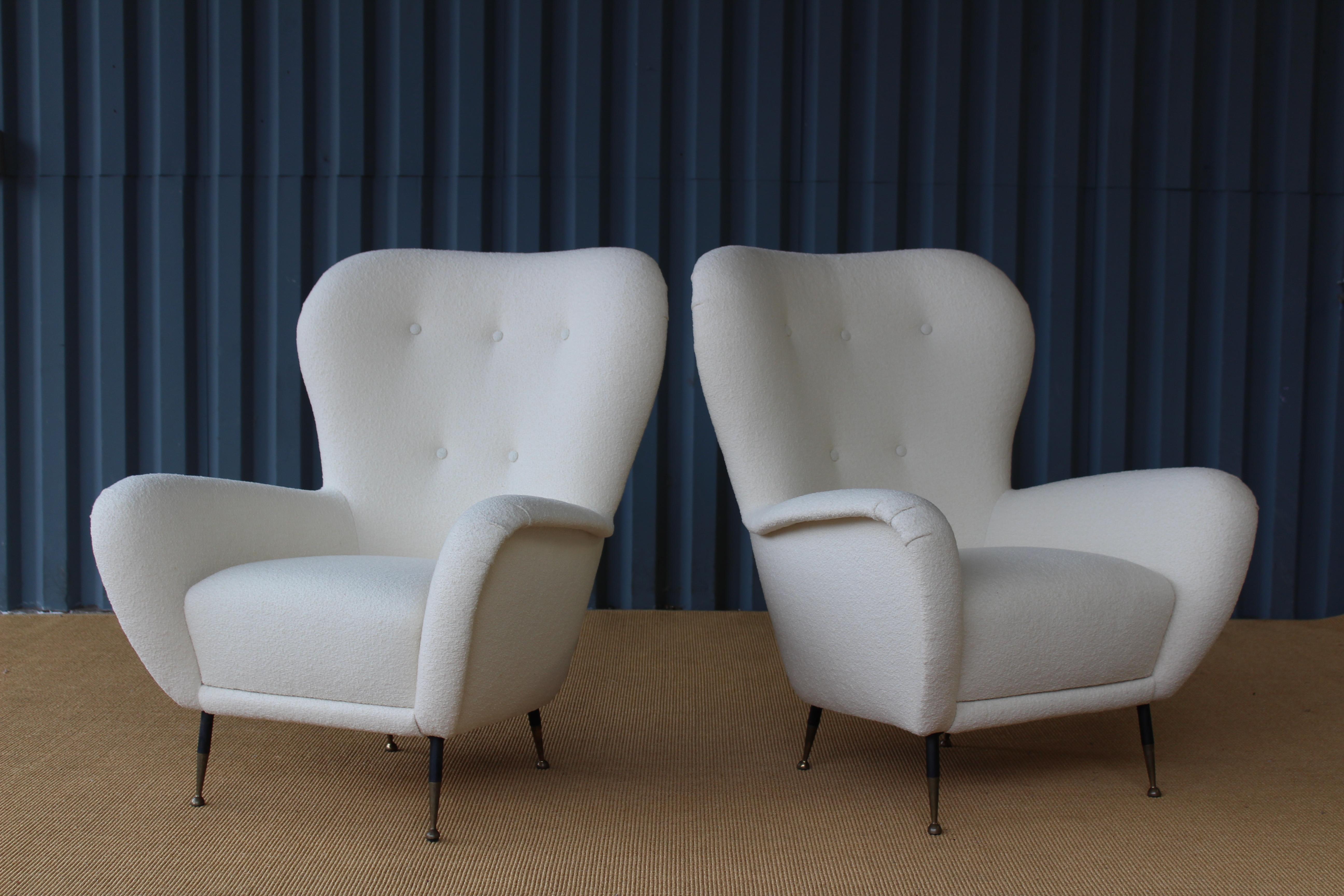 Pair of midcentury 1950s Italian armchairs. They sit on metal bases with brass feet. The pair feature new foam and have been reupholstered in a beautiful bouclé by Knoll.