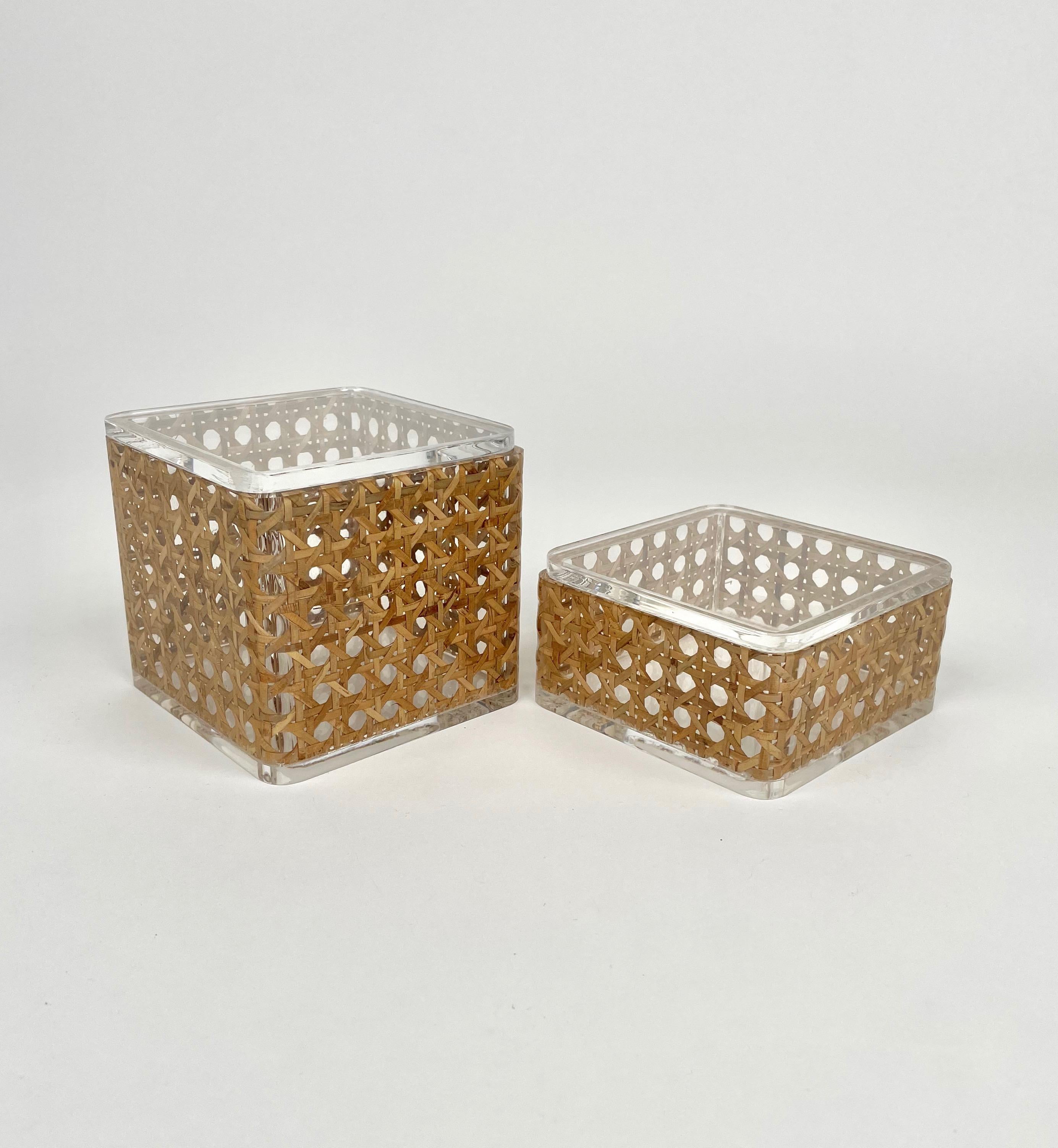 Pair of boxes in lucite and rattan in the style of Christian Dior Home. Made in Italy in the 1970s. 

The boxes come in different dimensions:
- Big box: 9.5 cm height x 10.5 cm diameter.
- Small box: 5.5 cm height x 10.5 cm diameter.