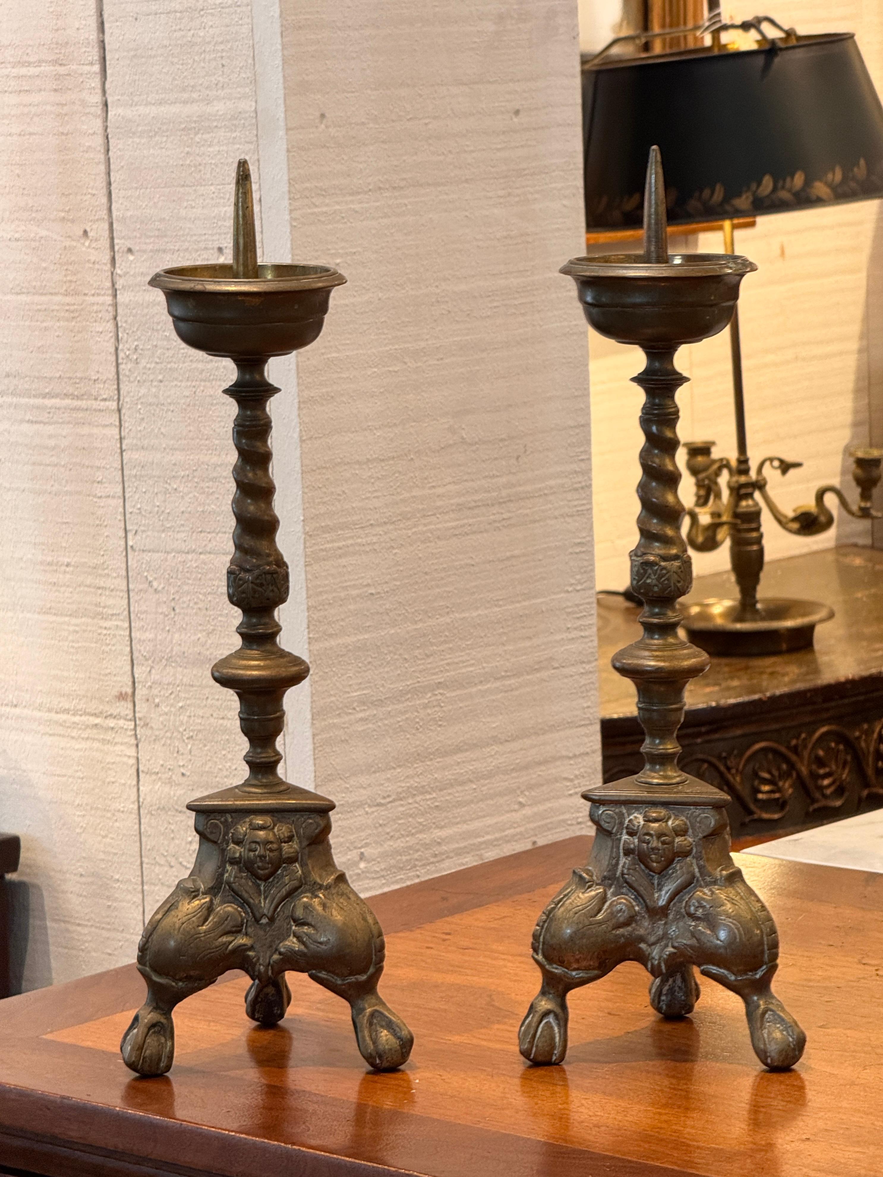 Un'impressionante coppia di bastoni d'altare in ottone con colonne tornite a spirale e basi fuse ornate da maschere cherubiche e piedi artigliati. Il design combina dettagli scultorei con proporzioni aggraziate e le superfici hanno sviluppato una