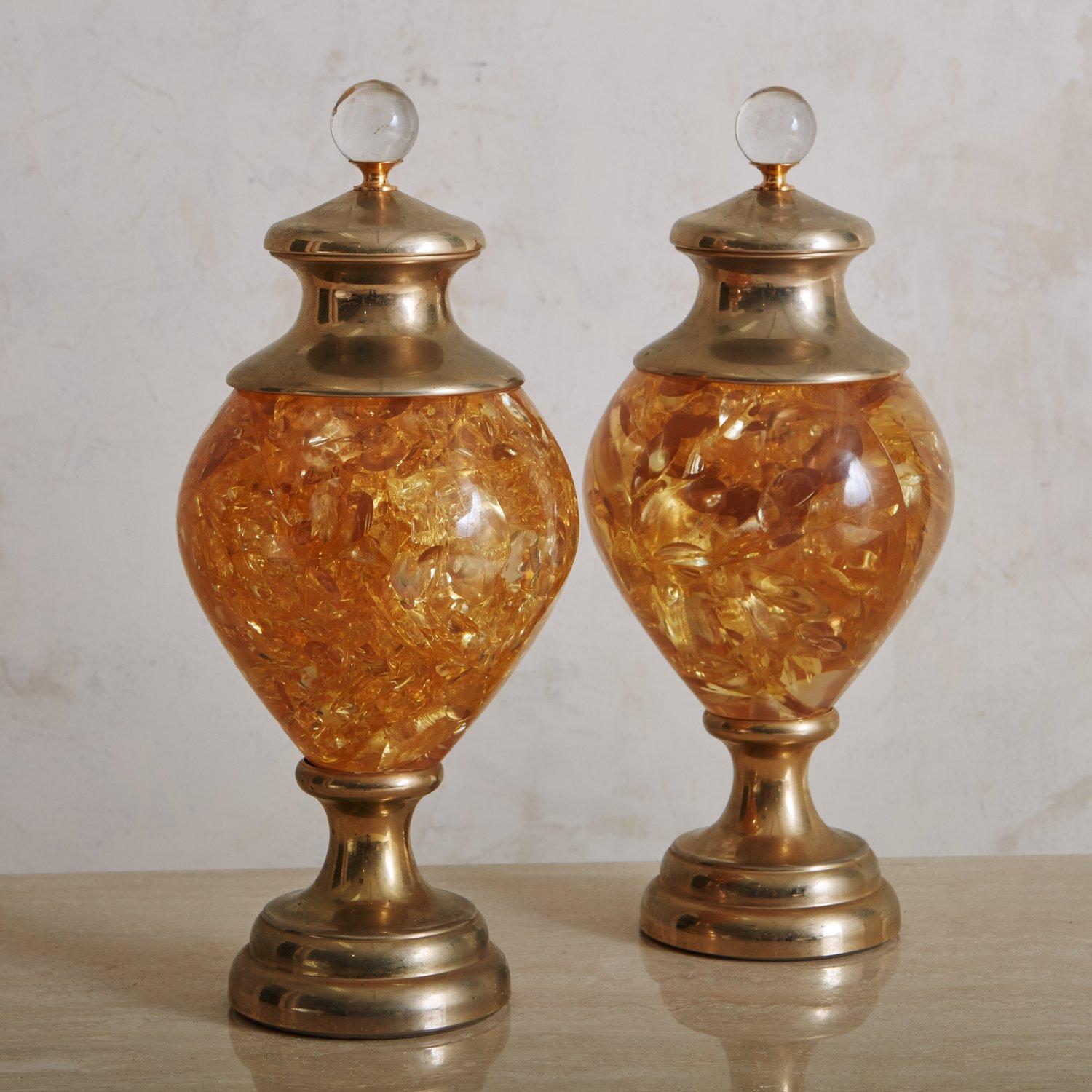 A pair of Mid-Century urns constructed with patinated brass and fractured amber resin. These urns have pedestal bases and circular glass ball details on the lids. Sourced in France, 1960s.
  